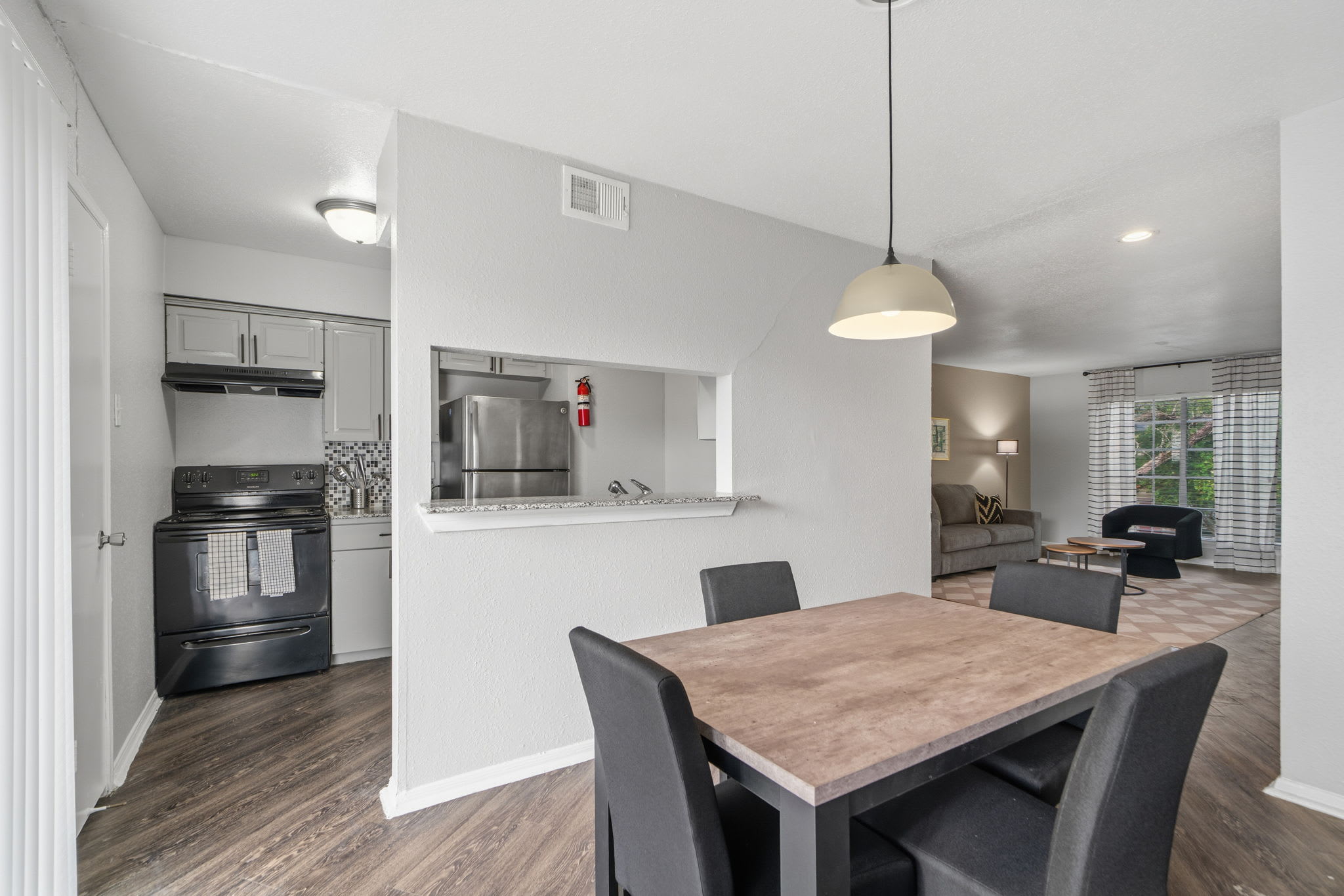 Open-plan dining area with seating for four, connected to a well-equipped kitchen and inviting living room with large windows.