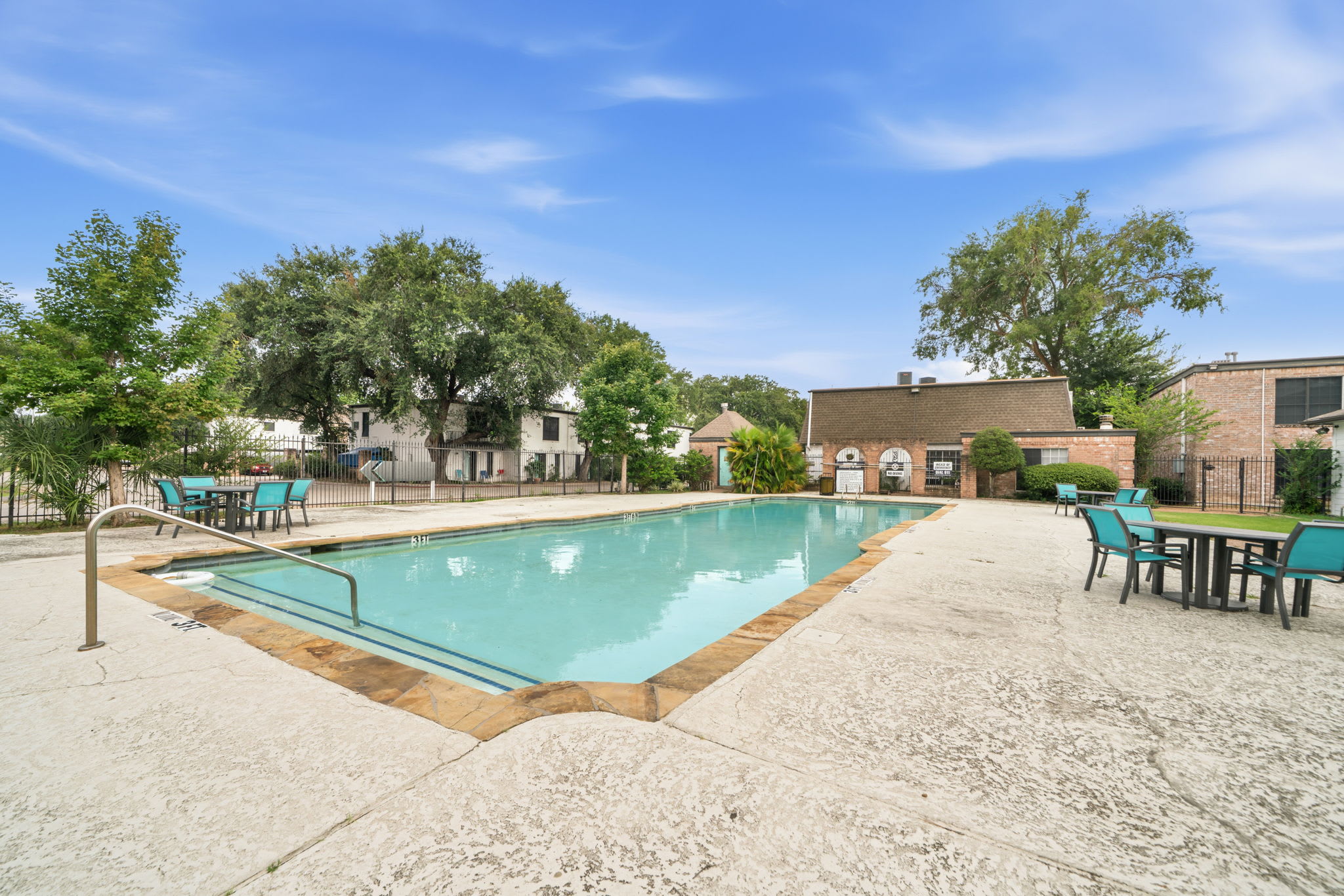 Shared outdoor pool with turquoise water, shallow entry, and ample turquoise seating for sunny days by the water.