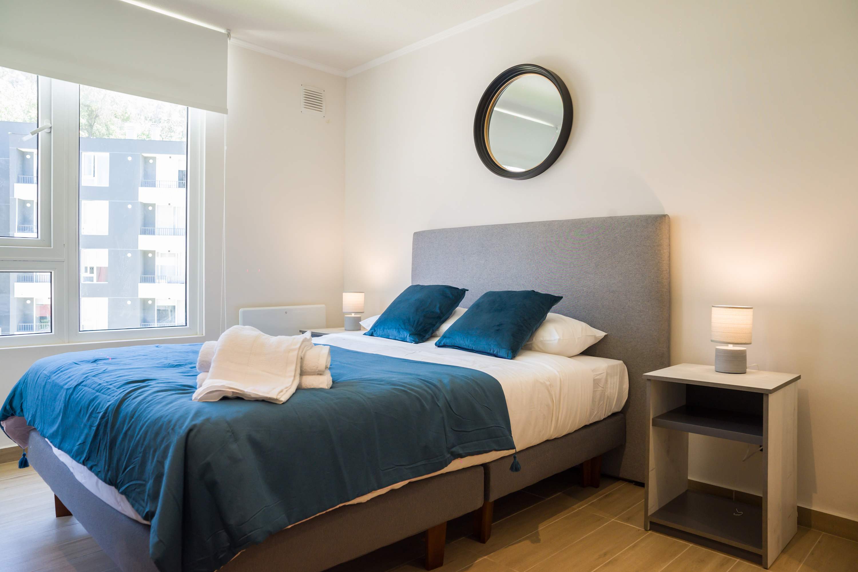 Private bedroom with two comfortable beds, crisp white linens, and deep teal bedding beside a bright window.