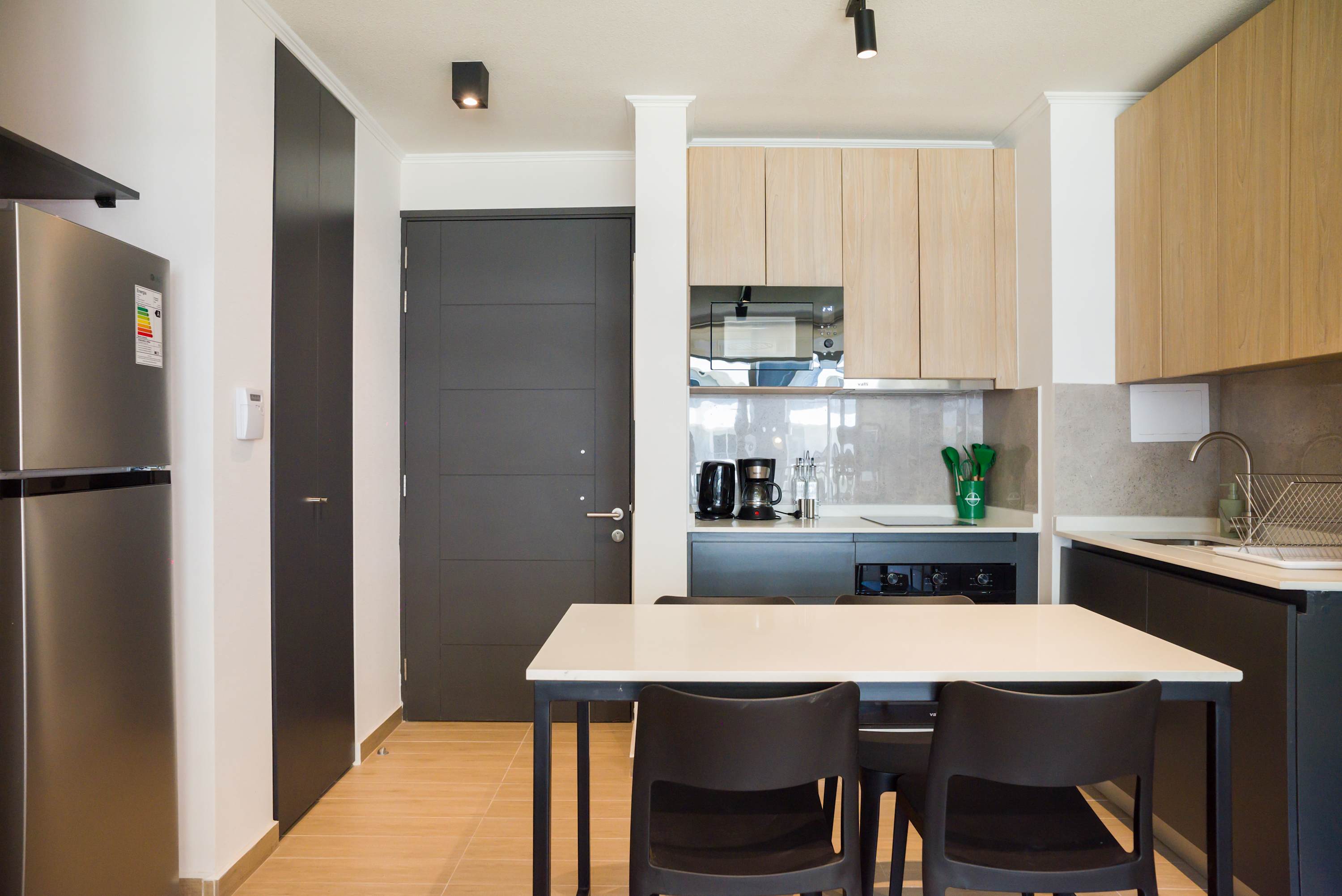 Modern private kitchen with light wood cabinetry, stainless-steel appliances, and a spacious white island with seating for shared meals.