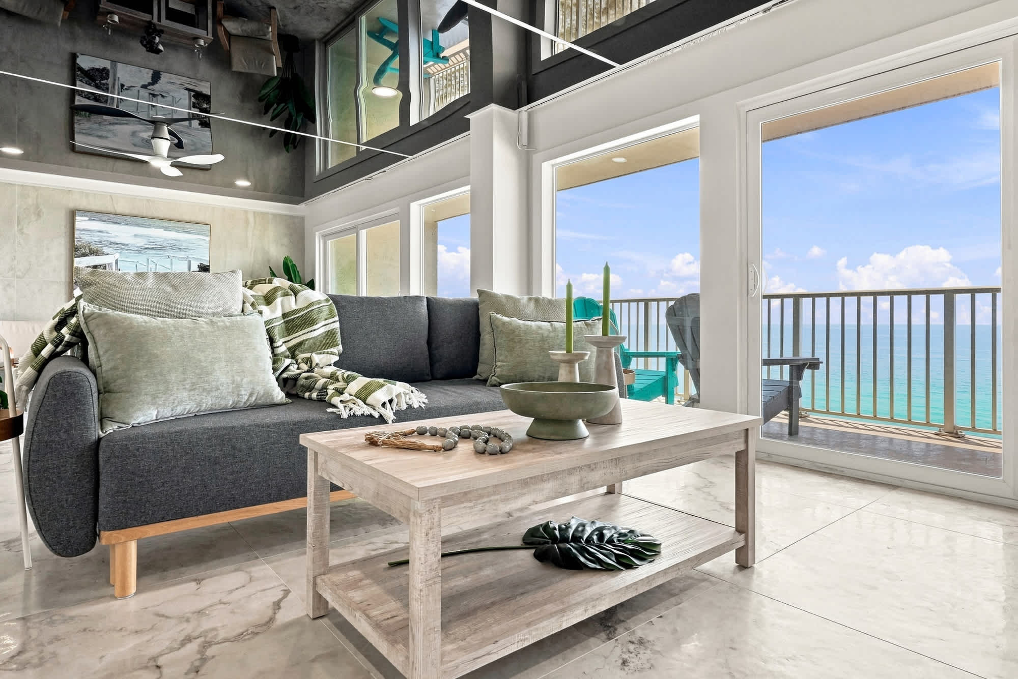 The Summit 1512 – Bright living room with a gray sofa, coffee table, and ocean view through large windows.