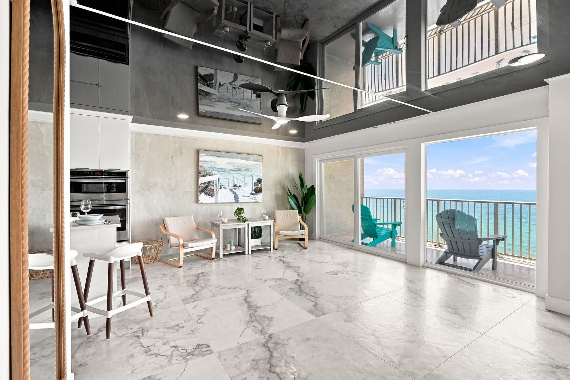 The Summit 1512 – Living room with ocean view, marble floor, chairs, and balcony access.