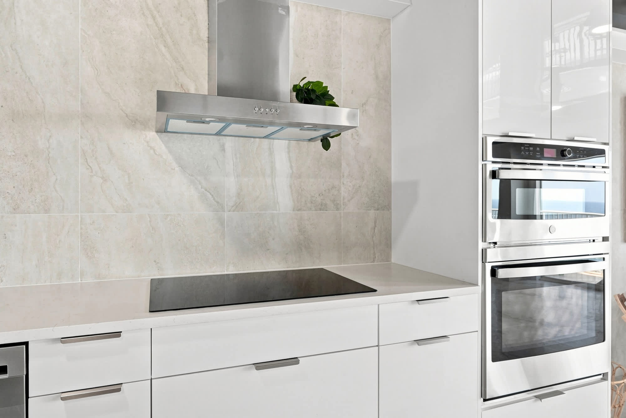 The Summit 1512 – Modern kitchen with white cabinetry, built-in double ovens, and a sleek cooktop under a stainless steel hood.