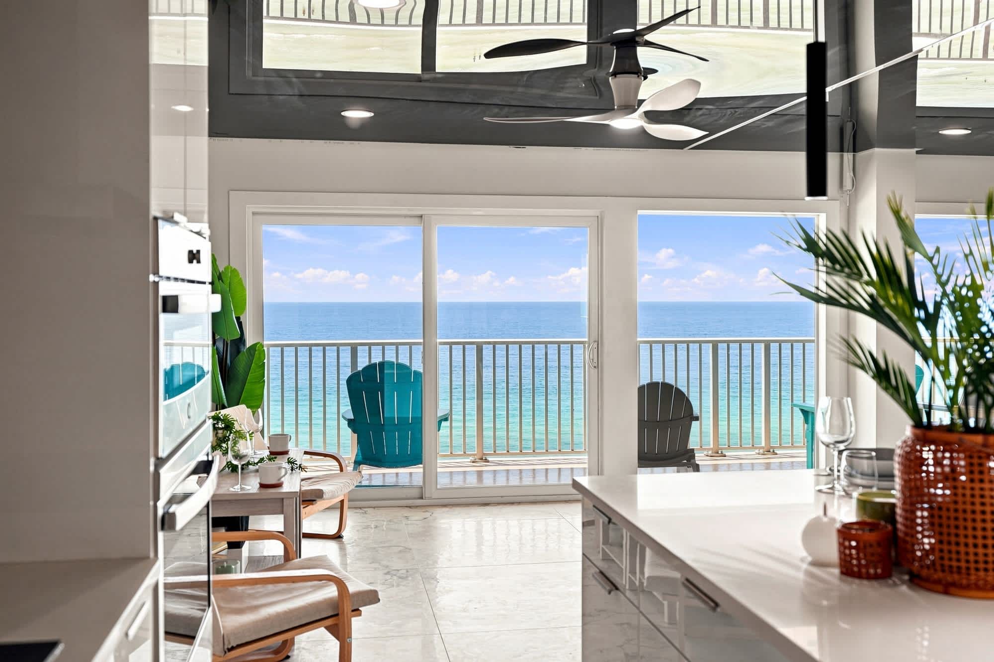 The Summit 1512 – Modern kitchen with ocean view, featuring a balcony with two chairs and decorative plants.