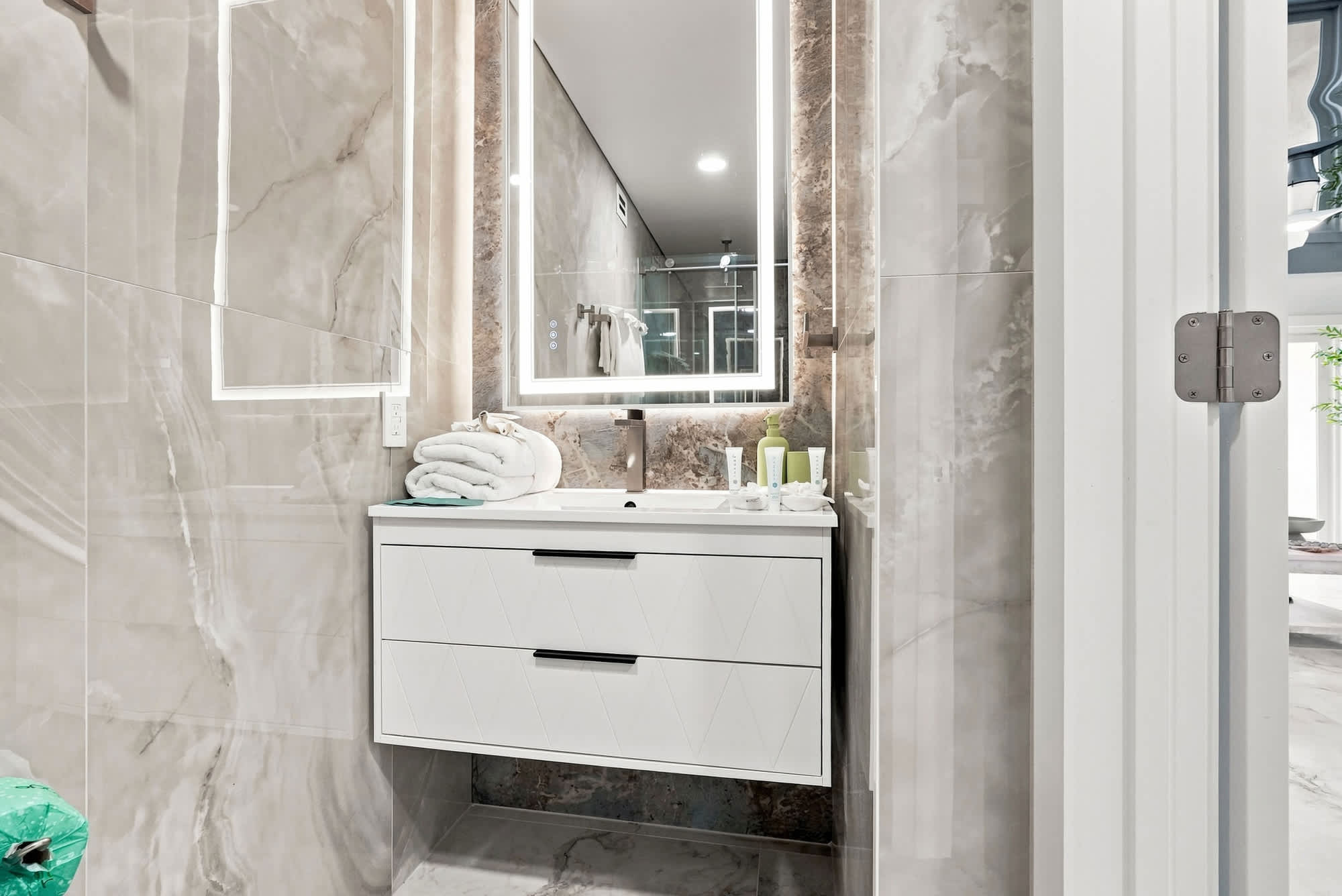The Summit 1512 – Modern bathroom with a double vanity, large mirror, plush towels, and sleek gray marble tiles.