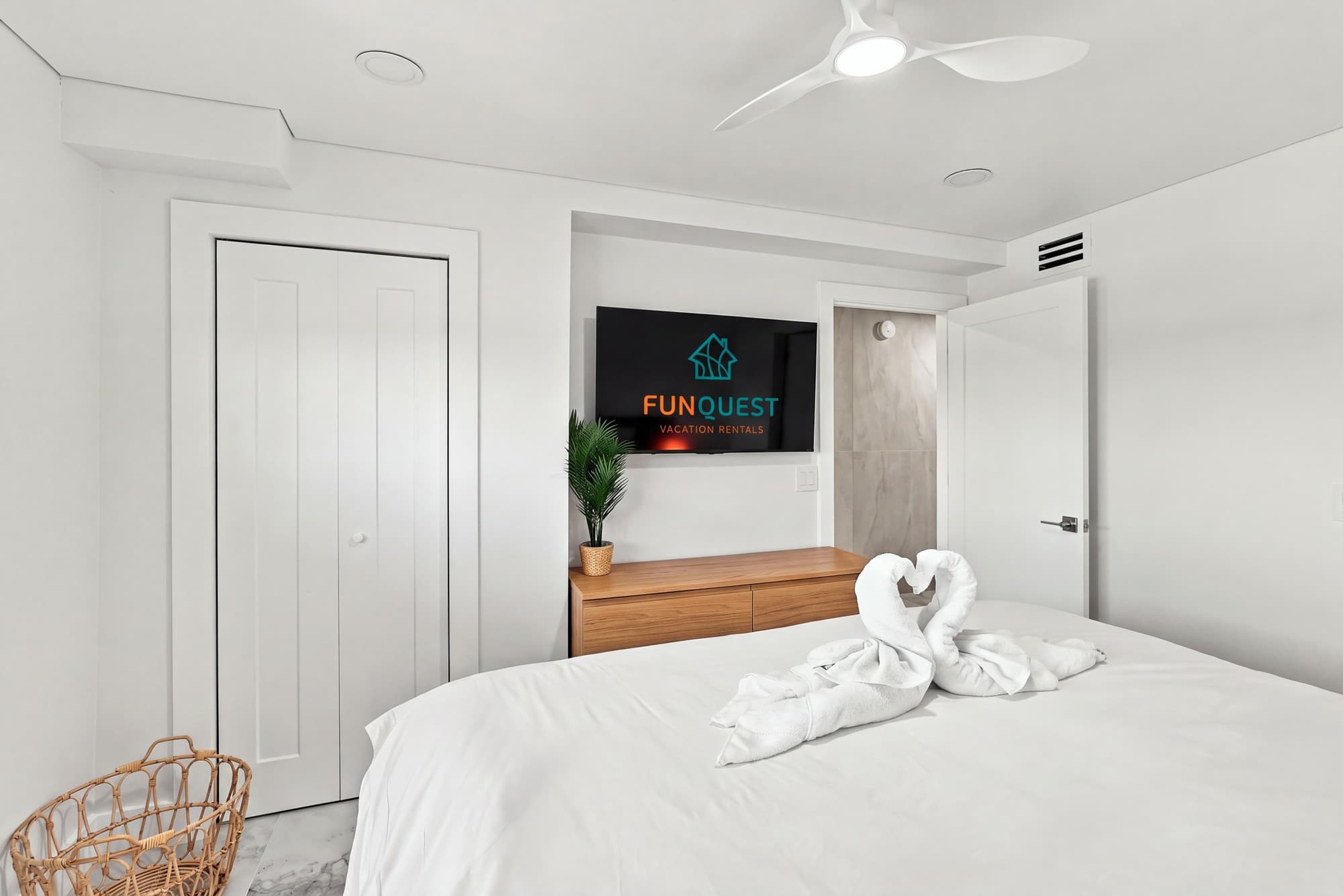 The Summit 1512 – Modern bedroom with a queen bed, TV, dresser, and a decorative towel sculpture.