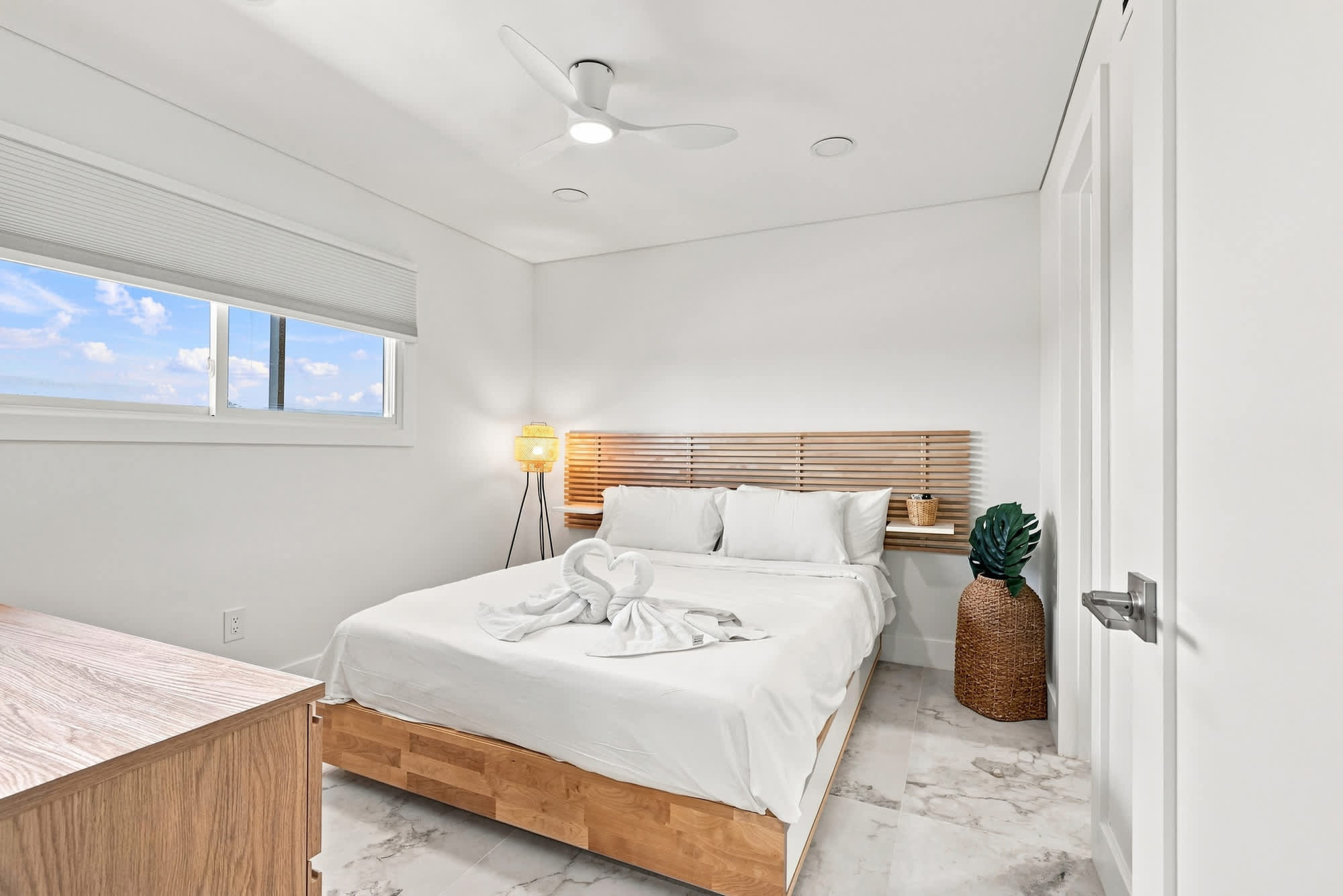 The Summit 1512 – Bright bedroom with a queen bed, wooden headboard, and a window showcasing a blue sky view.