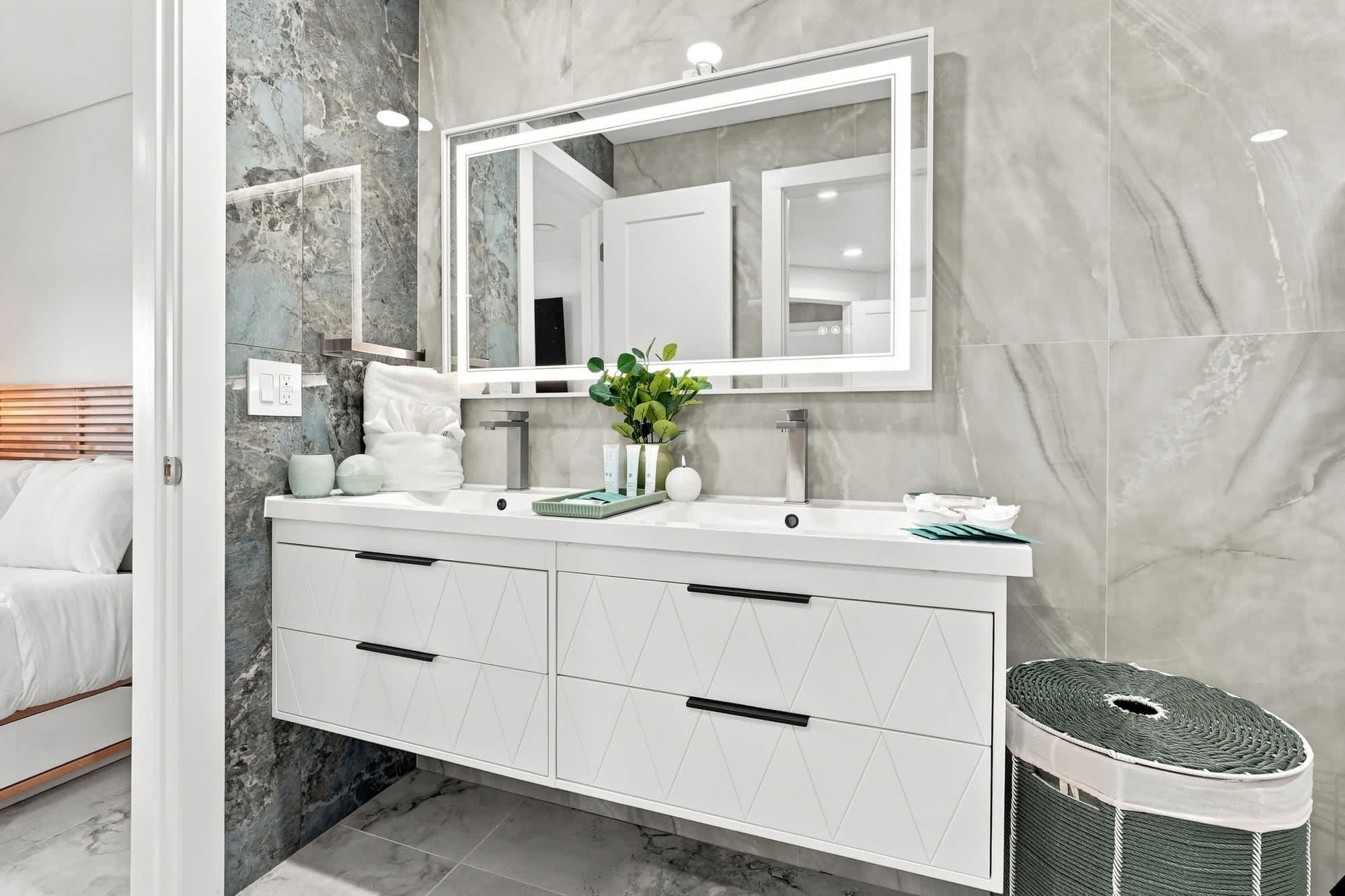 The Summit 1512 – Modern bathroom with dual sinks, large mirror, and decorative plant, featuring stone wall and storage basket.