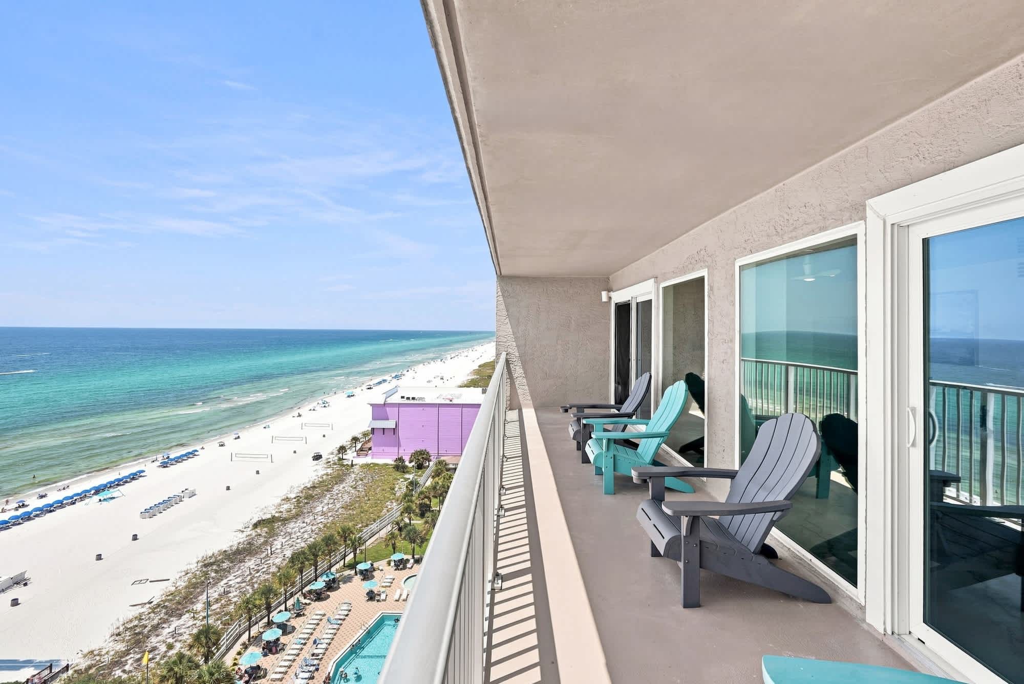 The Summit 1512 – Balcony with two chairs overlooking a beach and turquoise water.