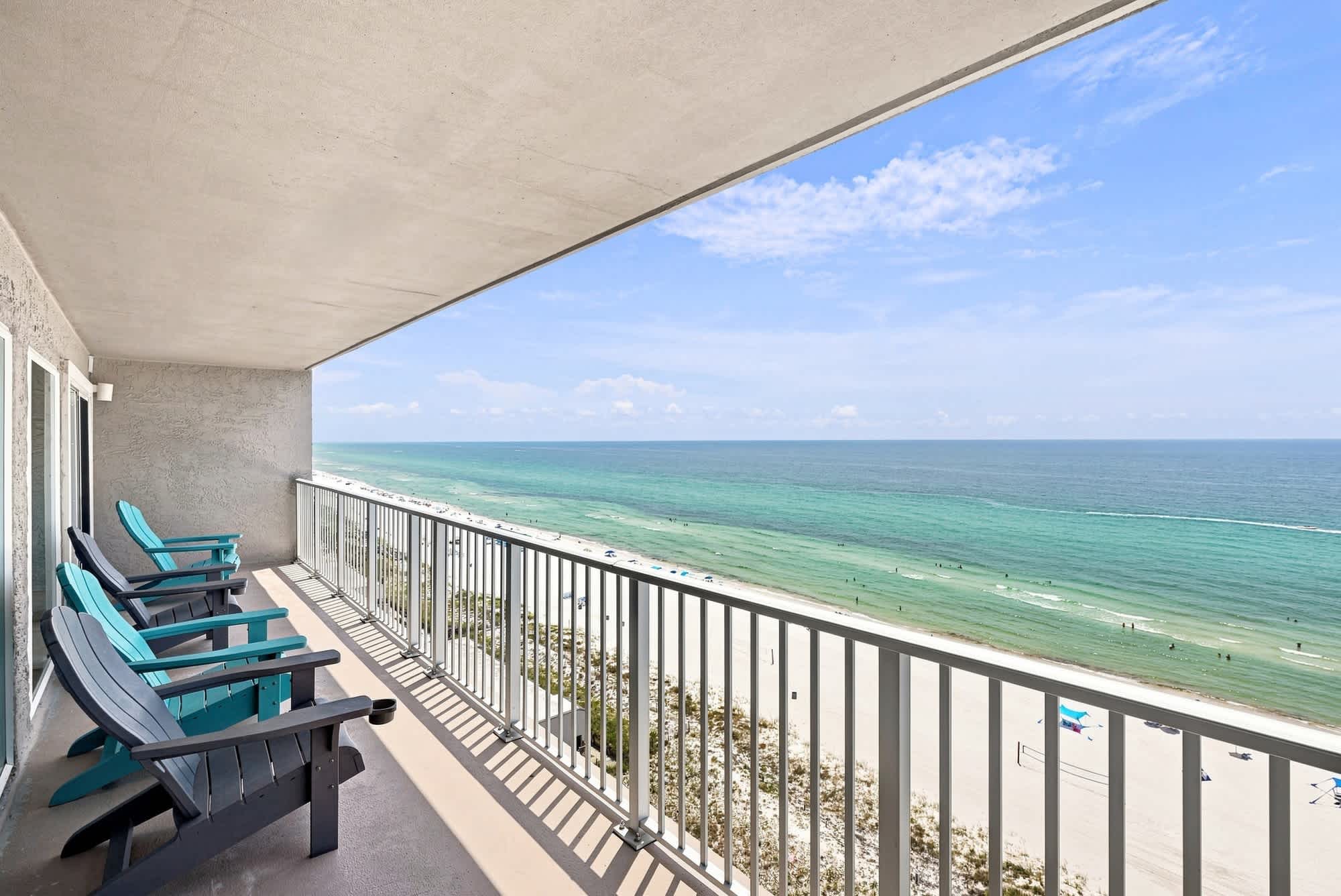 The Summit 1512 – Balcony view with four chairs overlooking the beach and ocean under a clear blue sky.