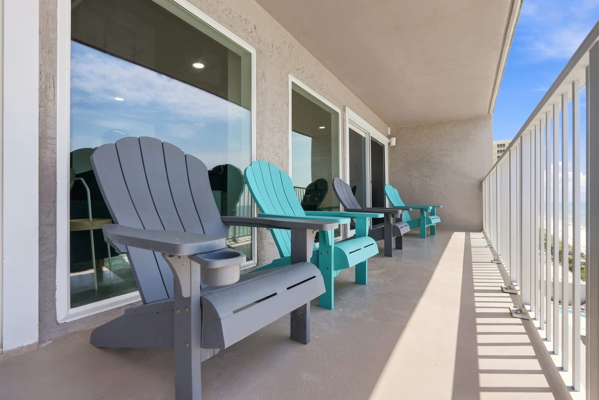 The Summit 1512 – Balcony with four colorful Adirondack chairs overlooking the ocean and blue sky.
