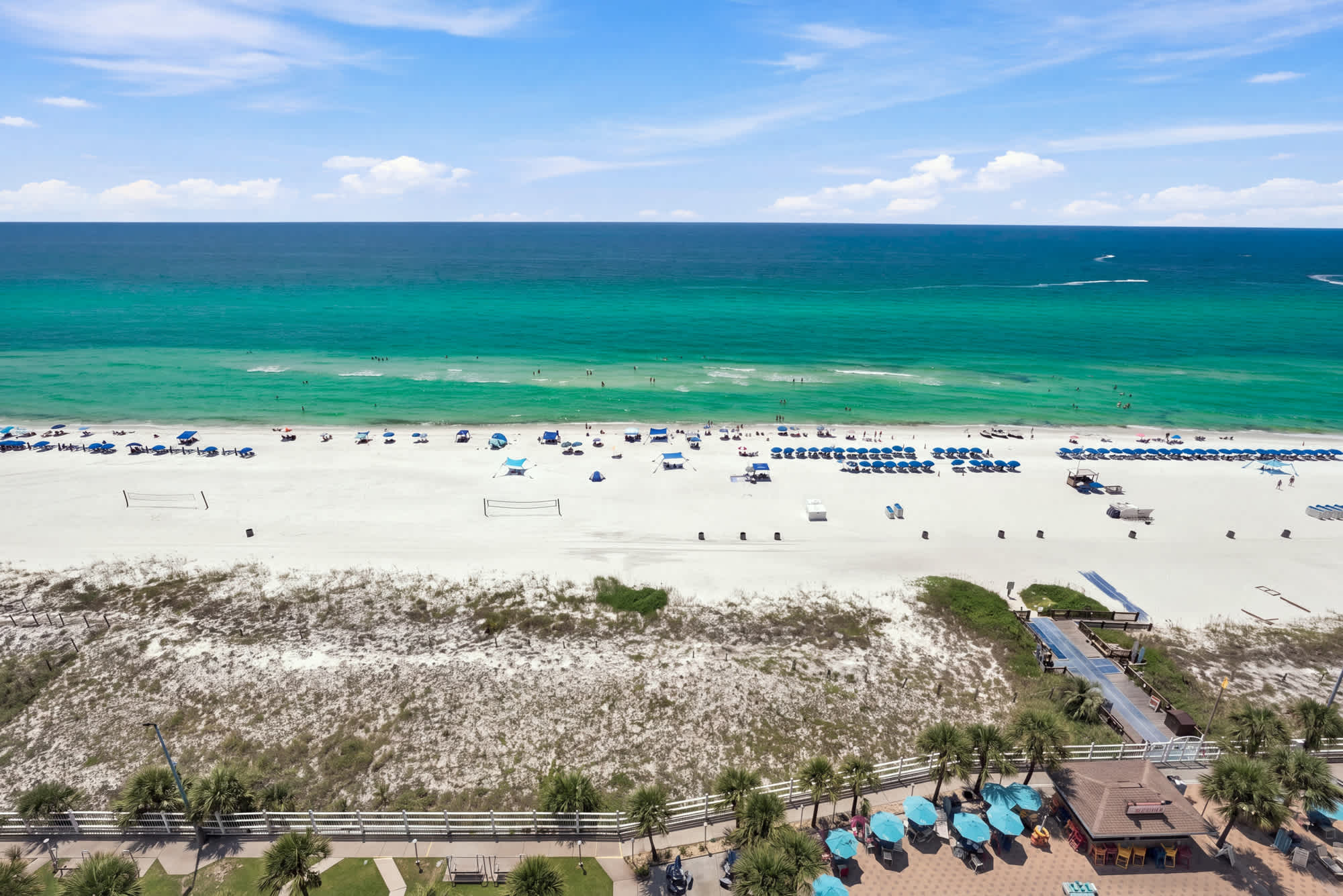 The Summit 1512 – Aerial view of a beach with lounge chairs, umbrellas, and turquoise water.