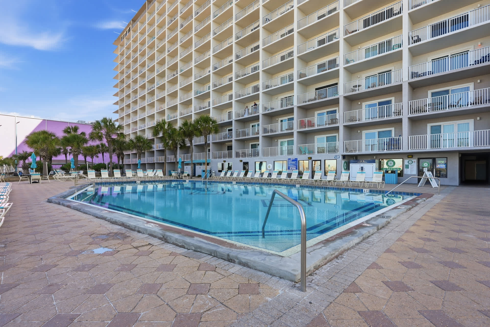 The Summit 1512 – Swimming pool with surrounding lounge chairs and a multi-story building in the background.