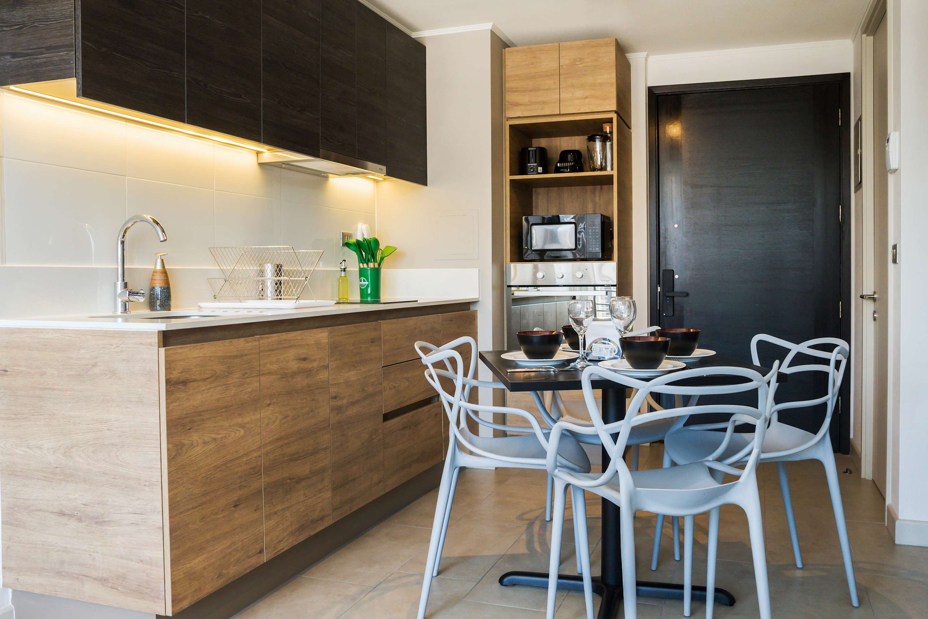 Modern private kitchen with warm wood cabinetry, full cooking appliances, and a dining table set for shared meals.