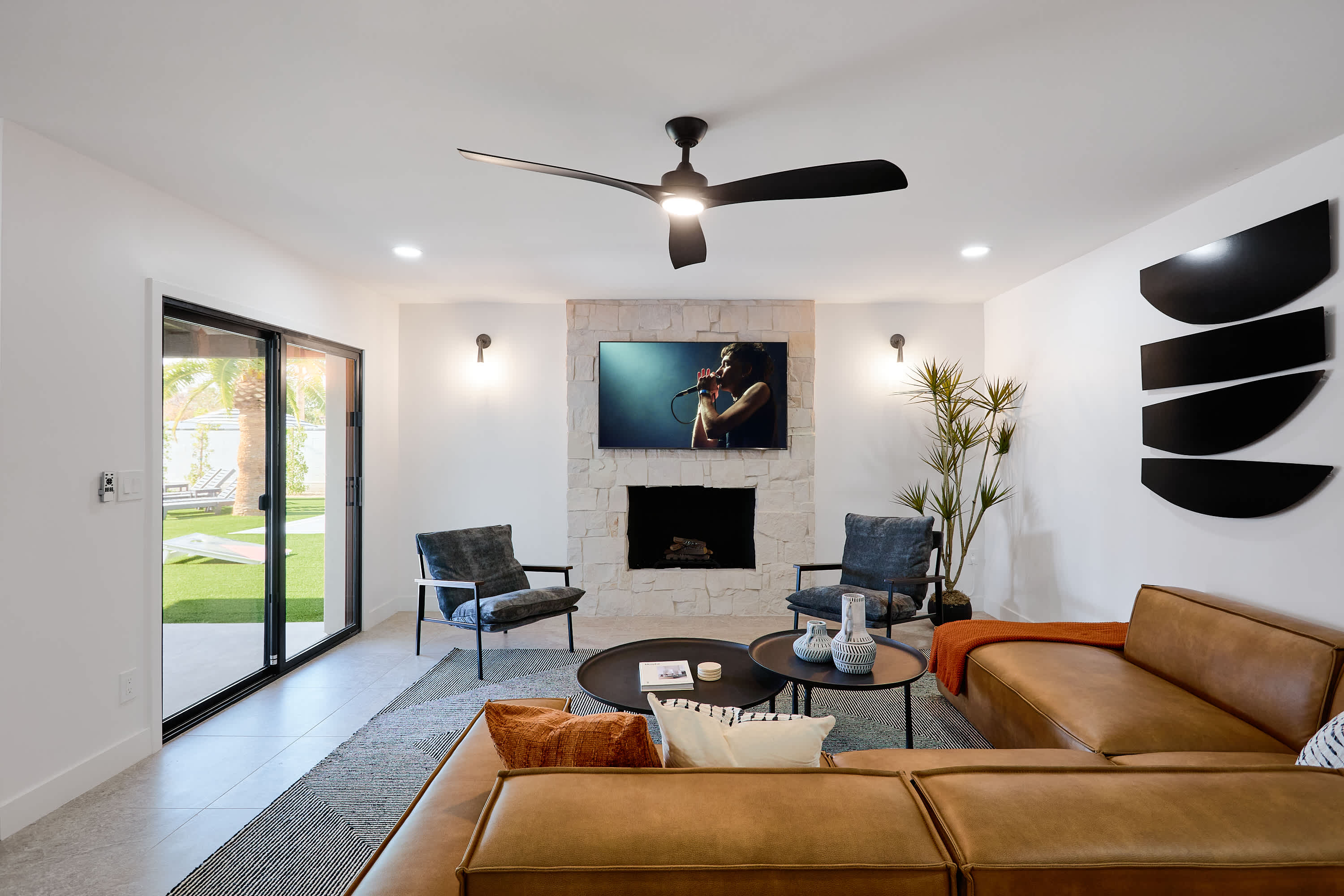 Bright and open concept living area with designer furnishings, smart TV, ceiling fan, and direct access to backyard.