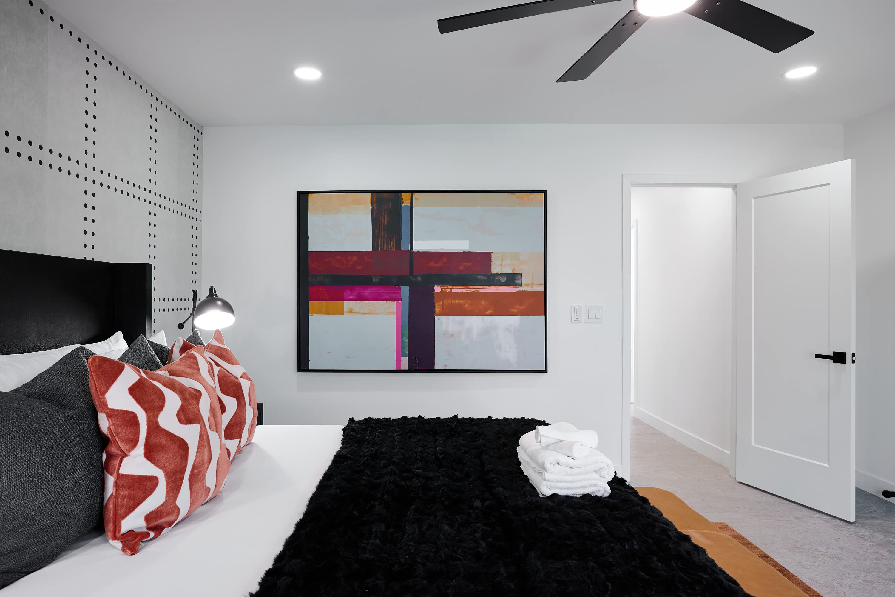Primary bedroom with King bed, designer furnishings, walk-in closet, smart TV, ceiling fan, direct access to backyard, work station, and en-suite bathroom.