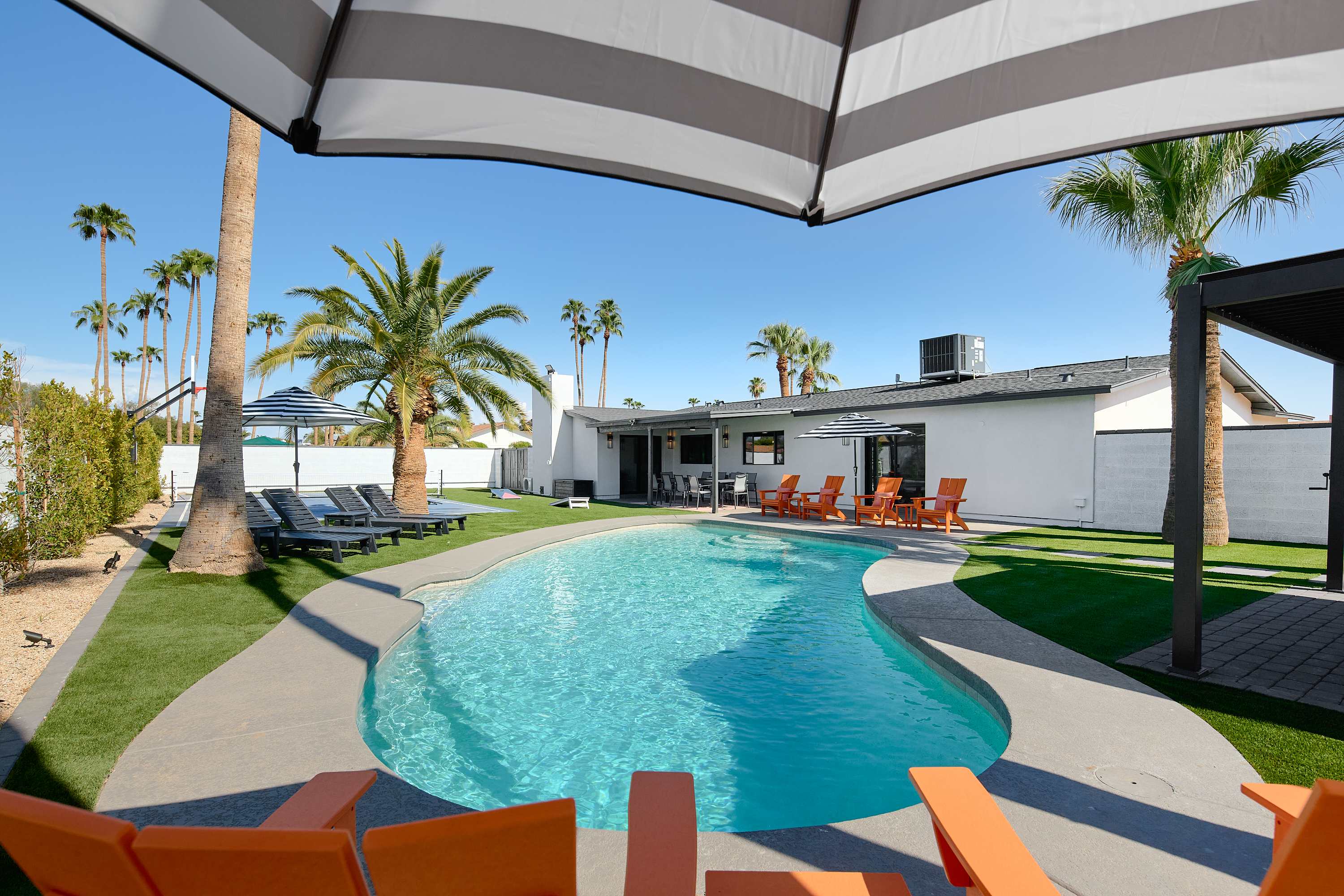 Private pool surrounded by poolside loungers, umbrellas, and multiple shaded seating areas.