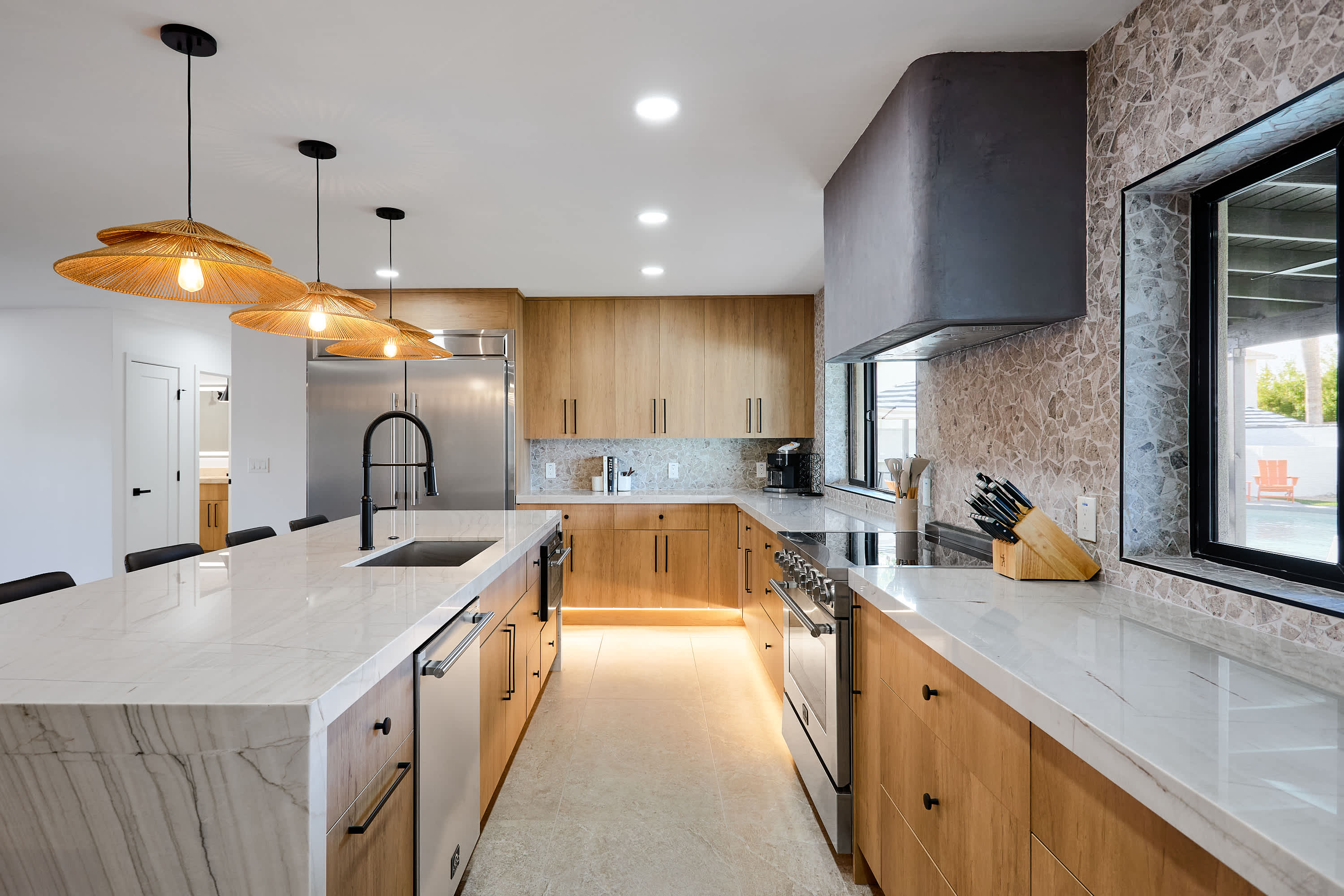 Sleek open concept kitchen with stainless steel appliances, large island with breakfast bar seating for 5, coffee bar with espresso machine, and fully equipped with your basic cooking essentials.