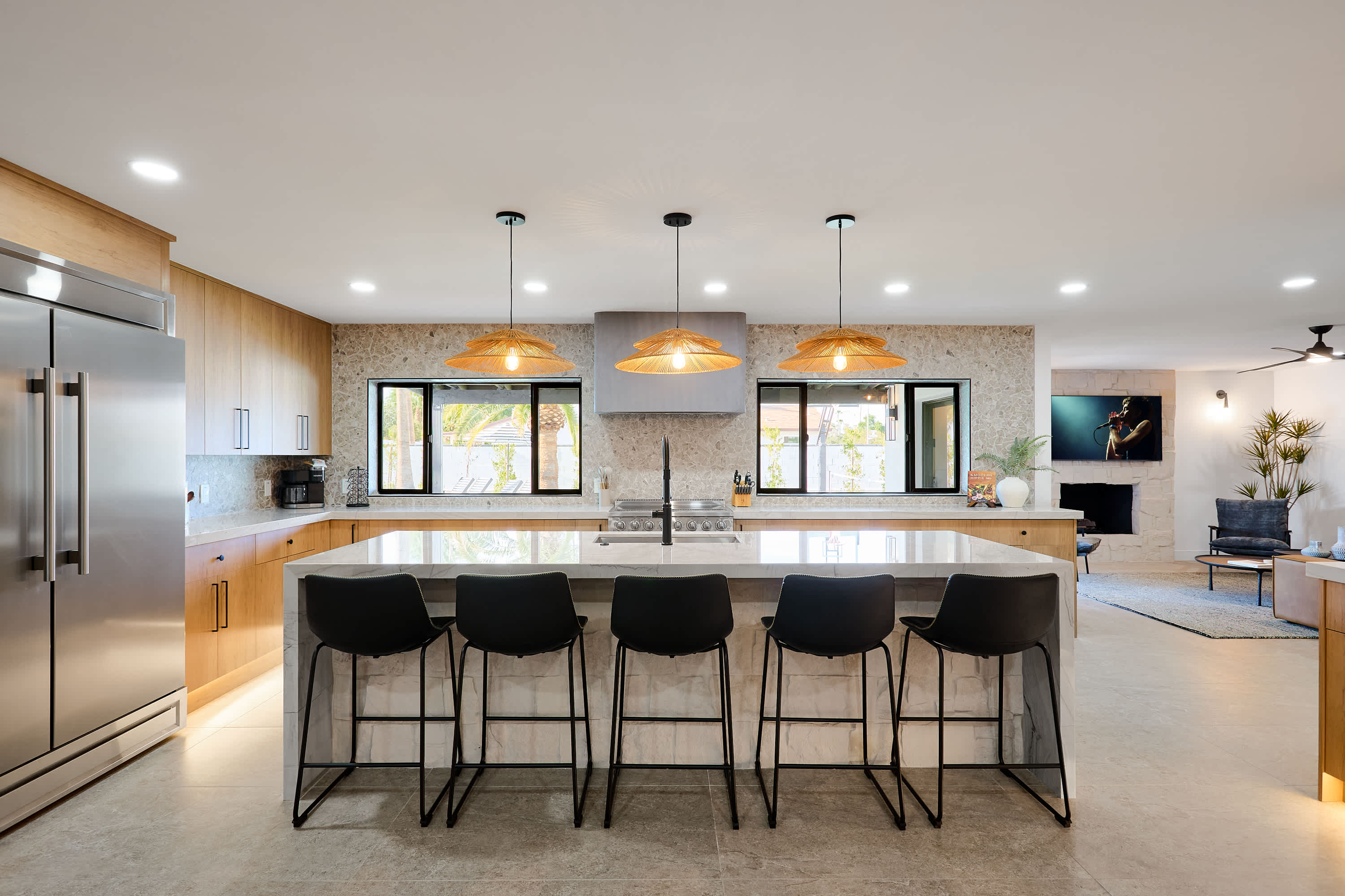 Sleek open concept kitchen with stainless steel appliances, large island with breakfast bar seating for 5, coffee bar with espresso machine, and fully equipped with your basic cooking essentials.