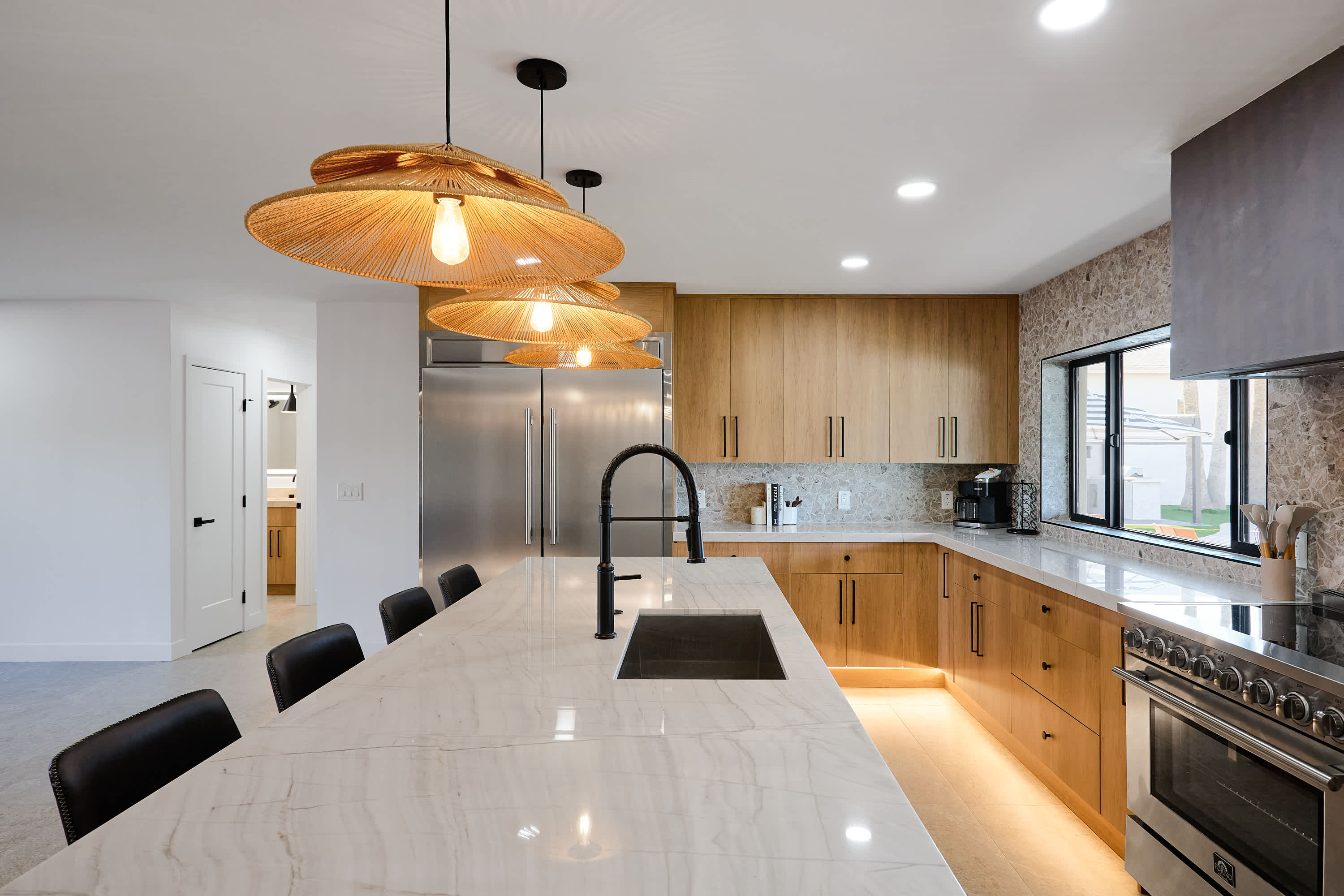 Sleek open concept kitchen with stainless steel appliances, large island with breakfast bar seating for 5, coffee bar with espresso machine, and fully equipped with your basic cooking essentials.