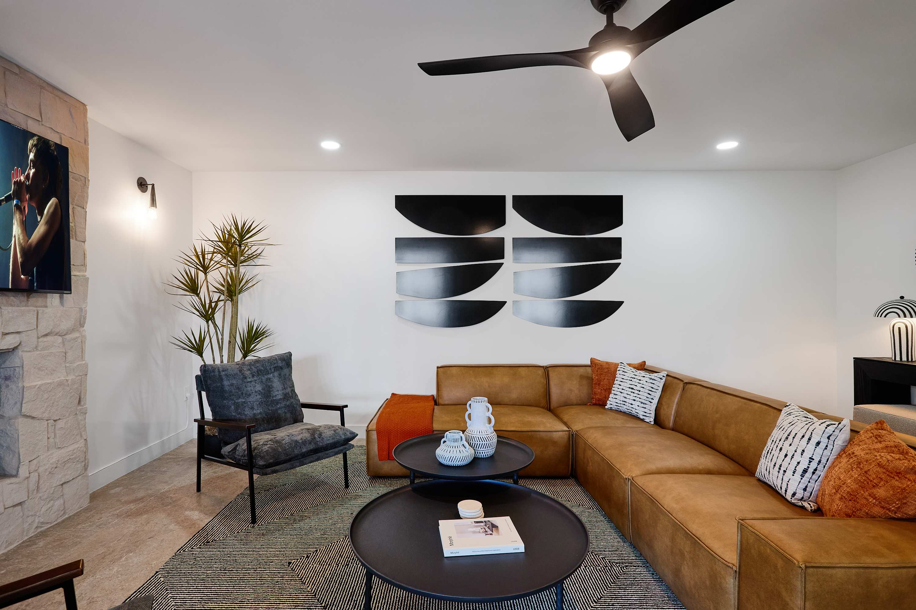 Bright and open concept living area with designer furnishings, smart TV, ceiling fan, and direct access to backyard.