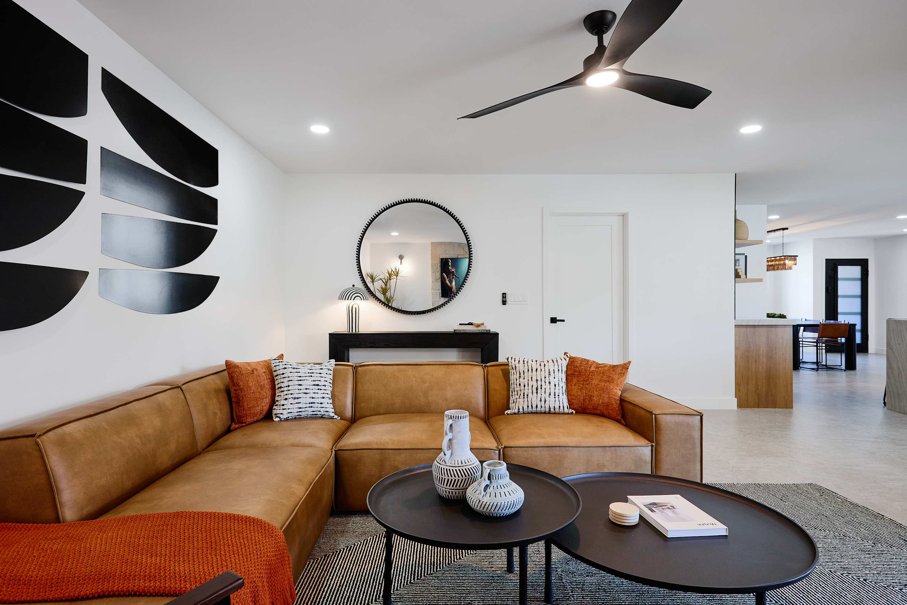 Bright and open concept living area with designer furnishings, smart TV, ceiling fan, and direct access to backyard.