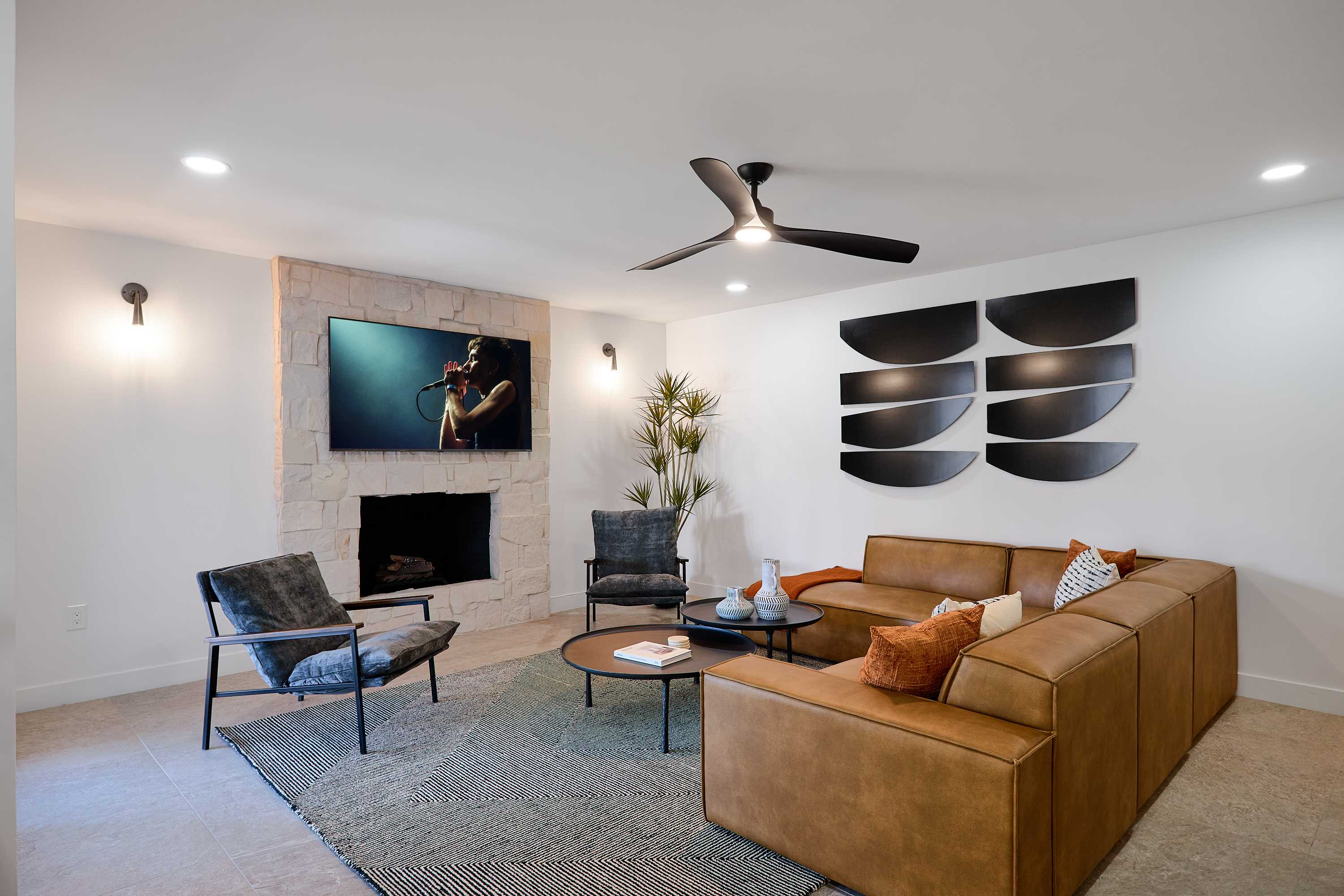 Bright and open concept living area with designer furnishings, smart TV, ceiling fan, and direct access to backyard.