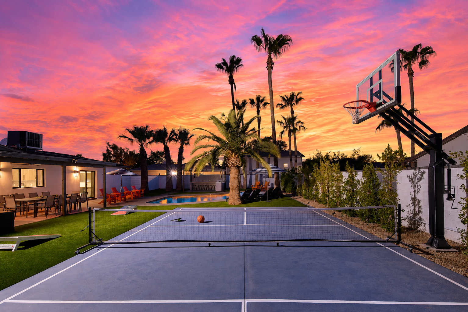 Resort-style backyard featuring a private pool, poolside loungers, a multi-sport court for basketball, pickleball, and tennis, turf with cornhole, a pergola with a built-in BBQ and bar seating, and a covered patio with outdoor dining table for 10.