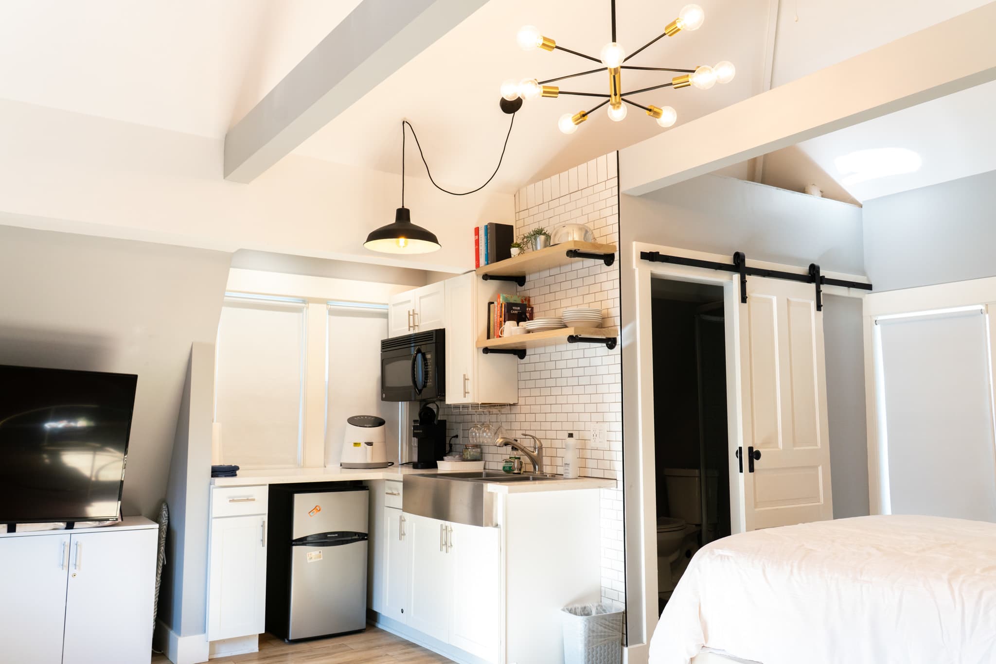Open shelving, subway tile, and pendant lighting bring warmth and character to the compact kitchenette.