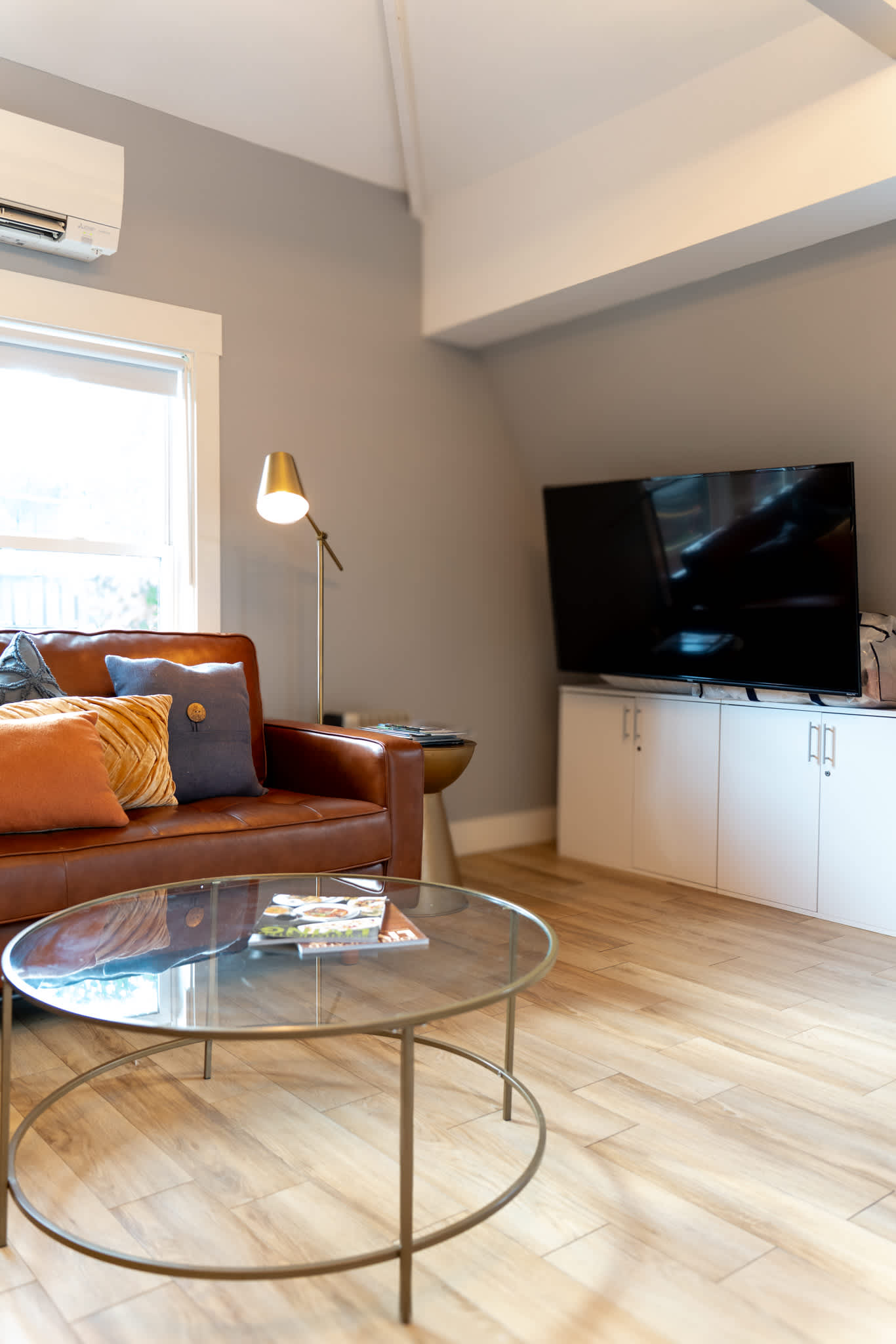 Unwind on the leather sofa with a favorite show, surrounded by soft light and warm wood tones.