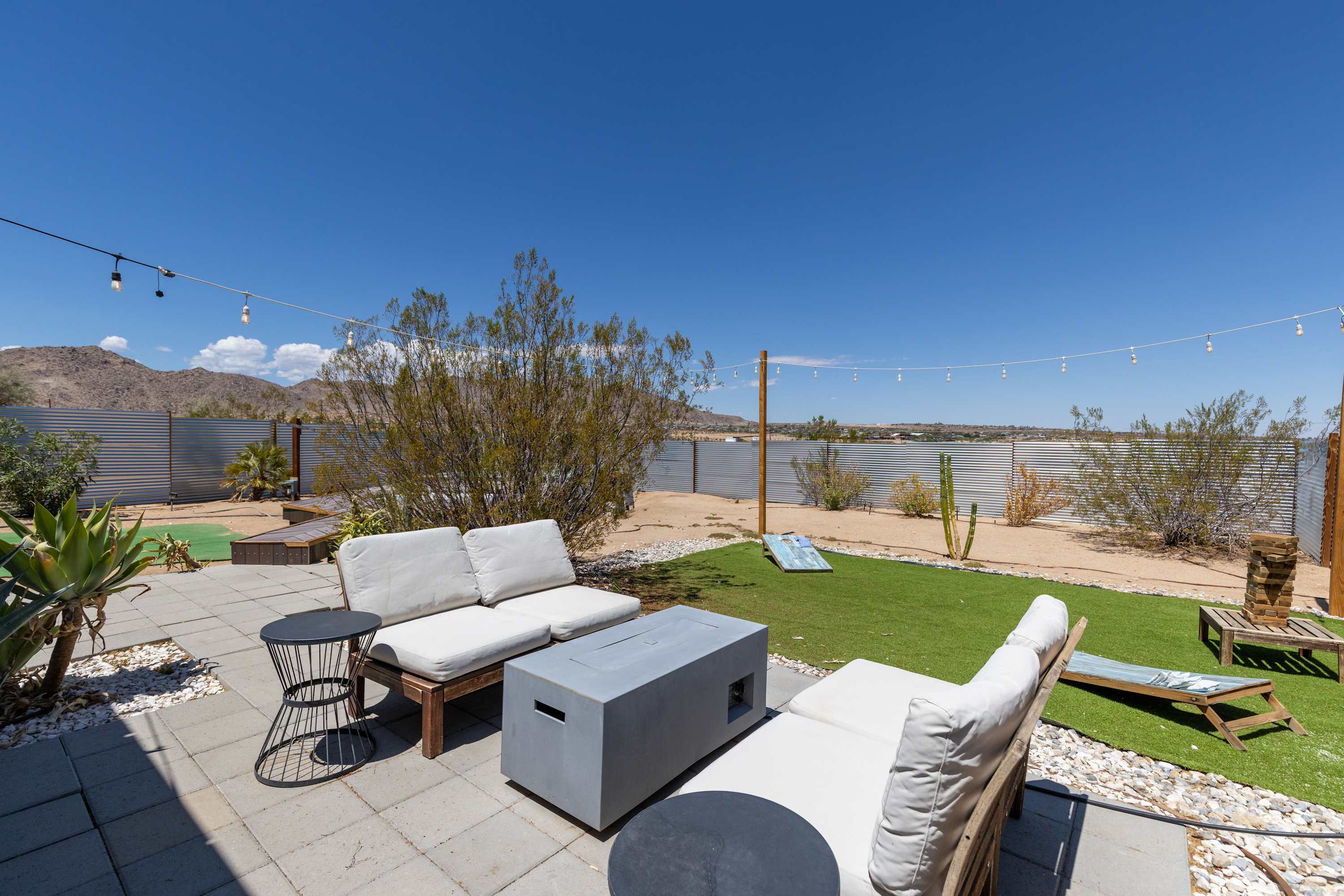 Studio courtyard seating around a fire table, with turf and desert mountain views.