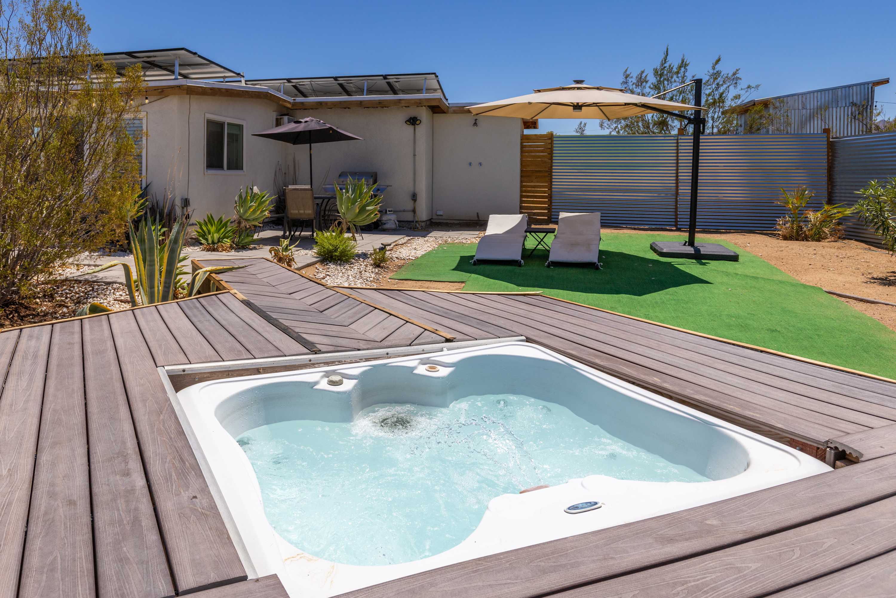 Studio spa inset in the wood deck beside the turf courtyard.