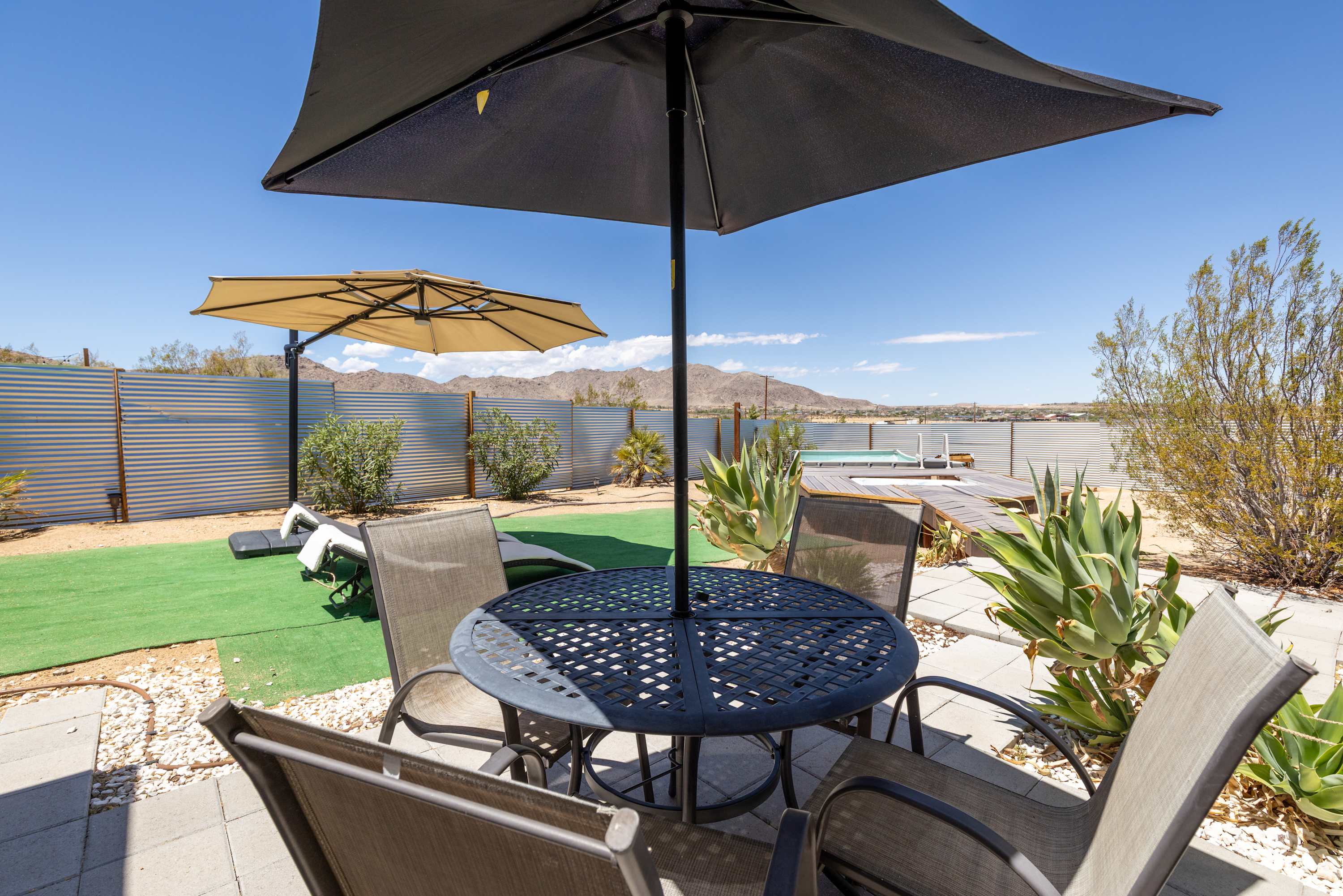 Outdoor dining table and chairs under umbrellas beside the studio courtyard.