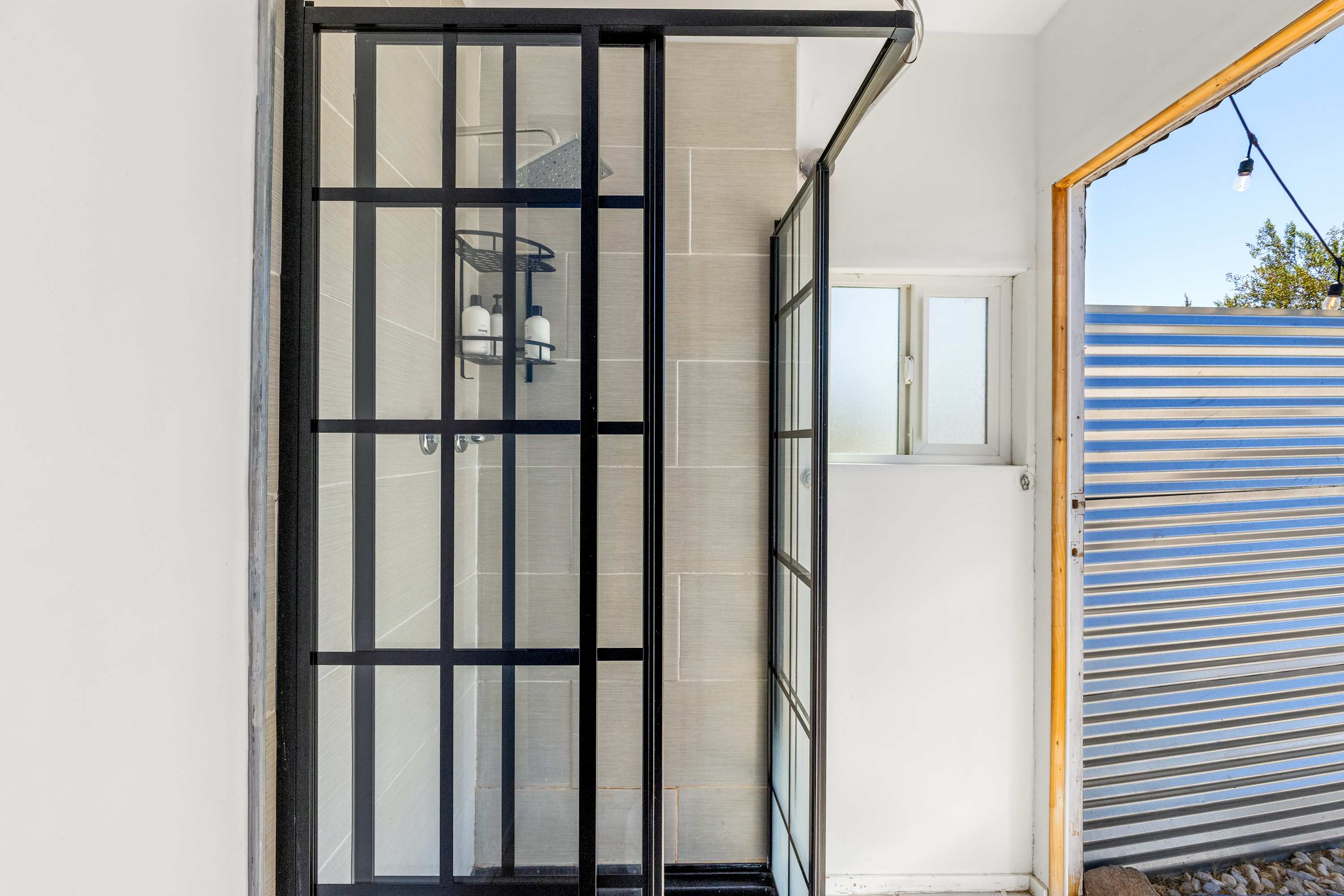 Second view of the black-framed glass shower in the outdoor bathroom.