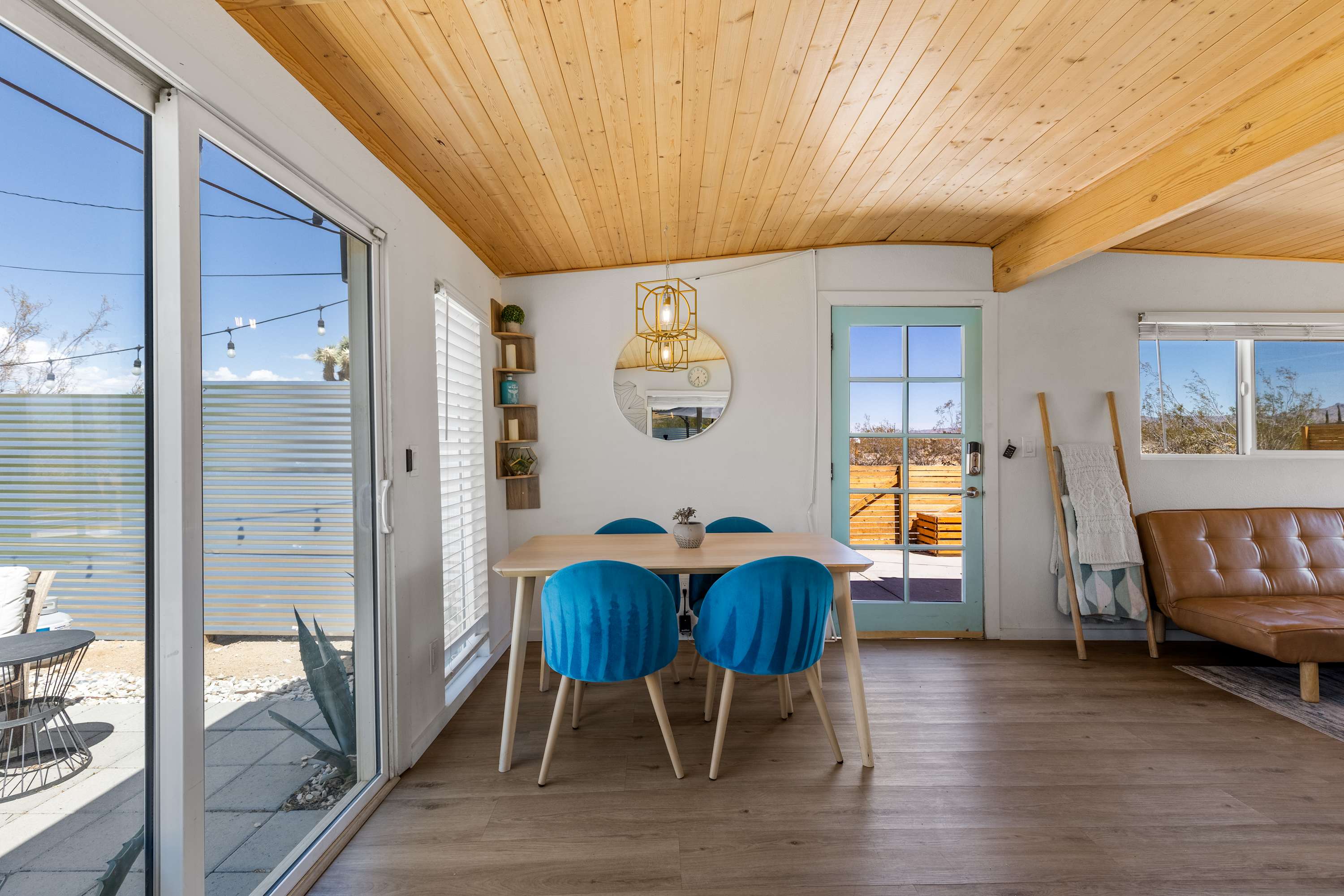 Studio dining nook with a round table, blue chairs, pendant light and glass door.