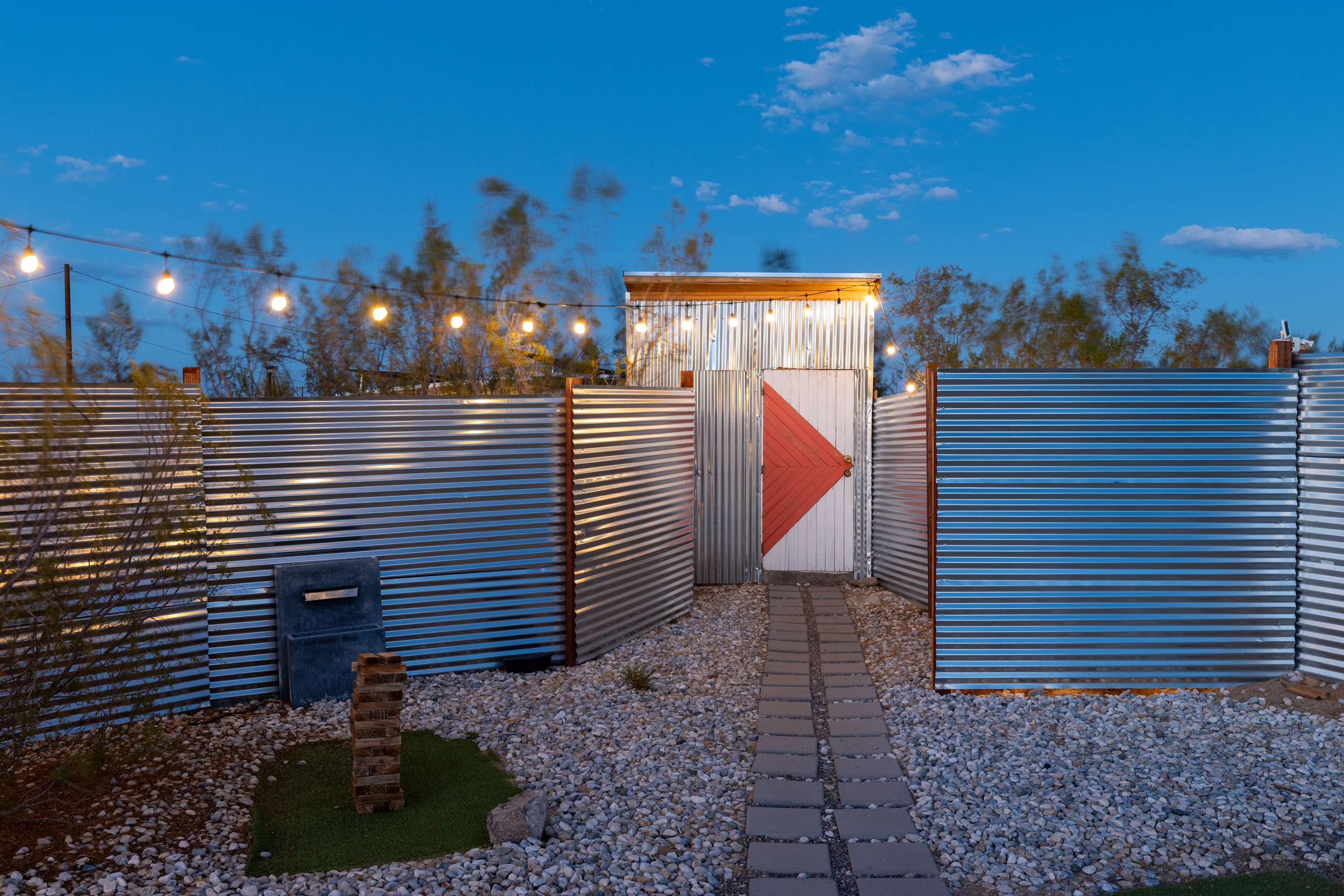 Airstream courtyard entrance gate at dusk beneath illuminated string lights.