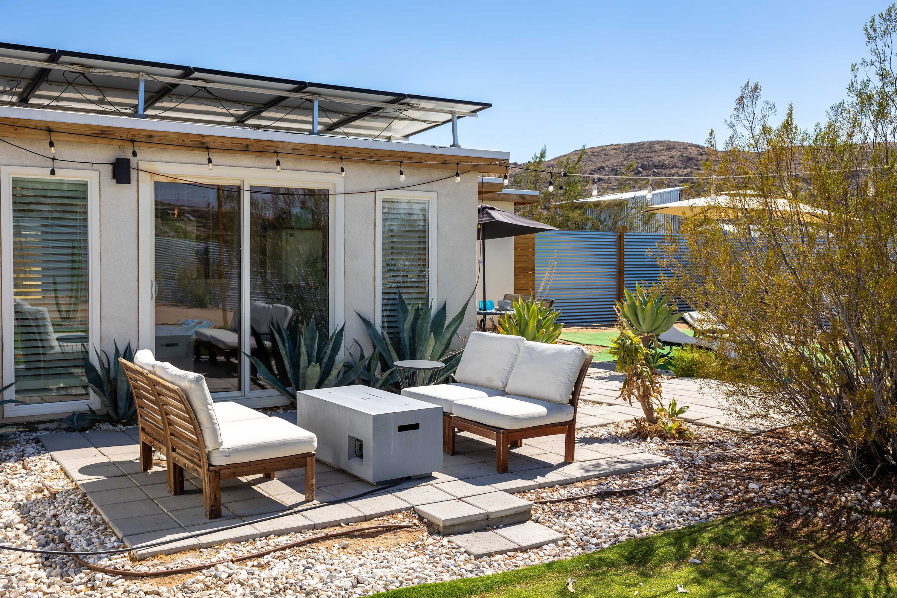 Studio front patio with cushioned chairs, fire table and sliding glass doors.