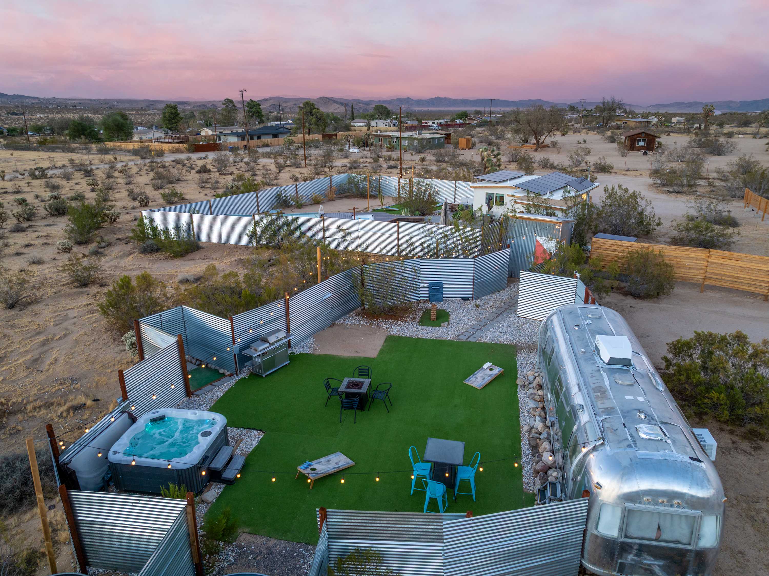 Sunset aerial view of the fenced Airstream courtyard, spa and surrounding desert.