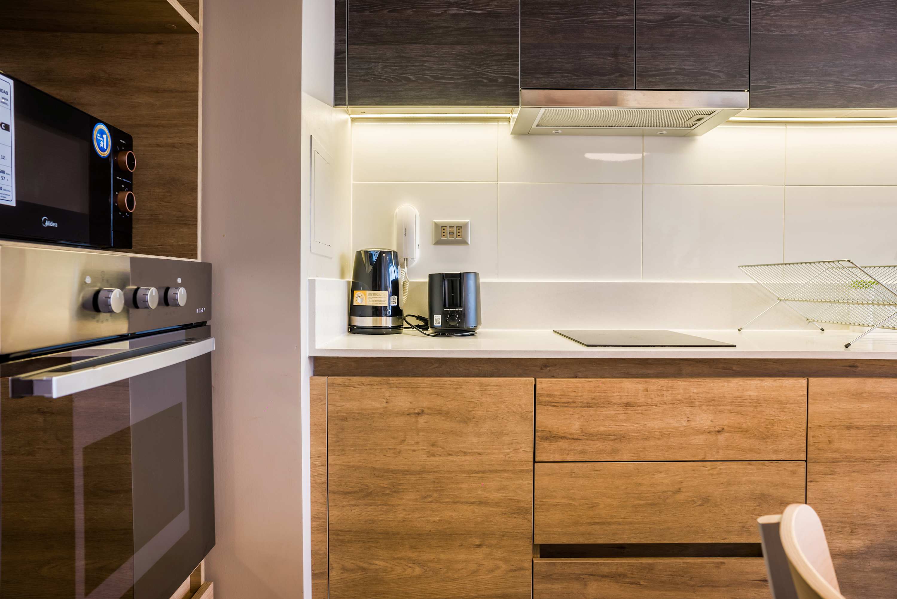 Private kitchen with warm wood cabinetry, a modern cooktop, and convenient coffee and tea appliances.