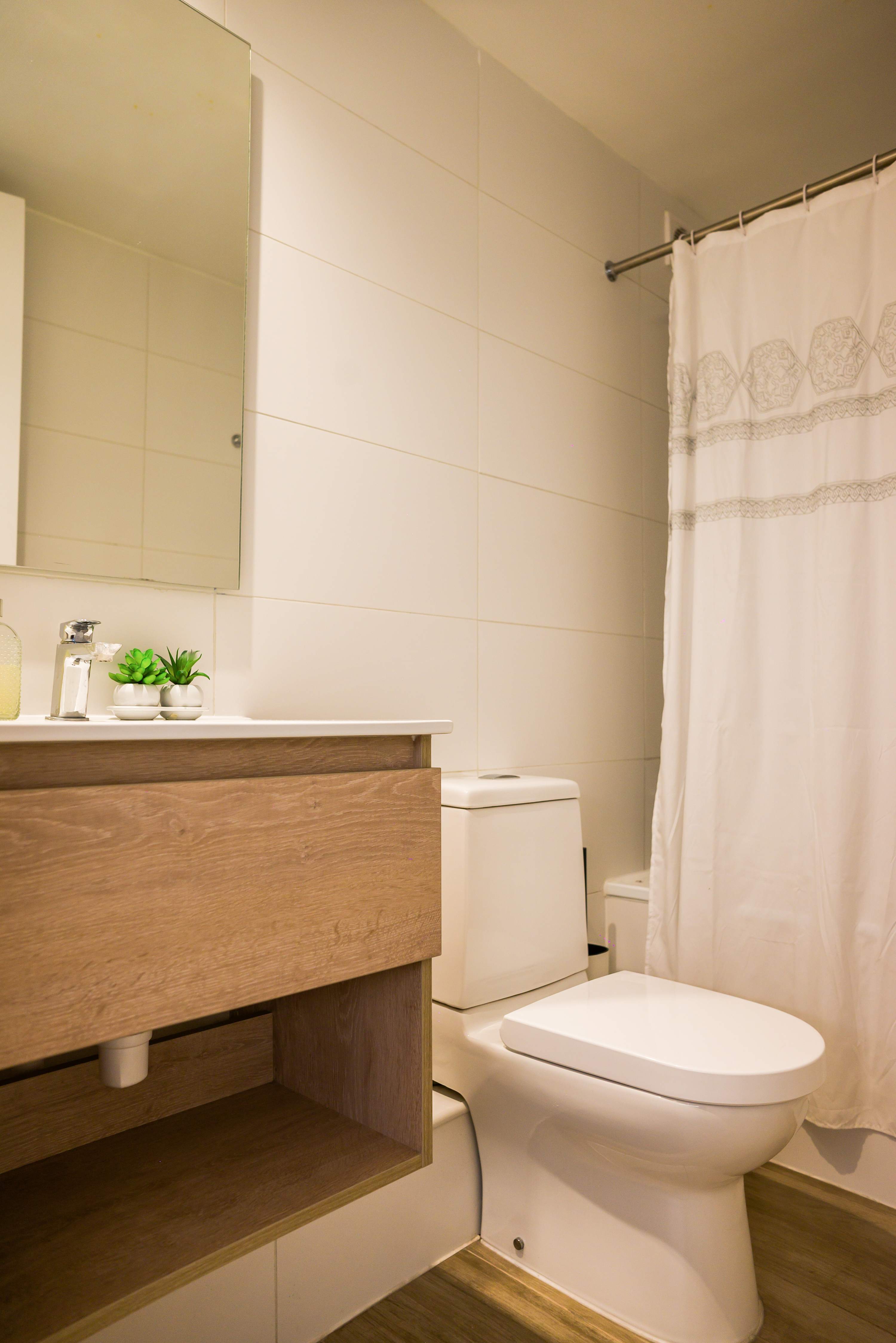 Private bathroom with a wood-finish vanity, mirrored cabinet, and a patterned shower curtain.