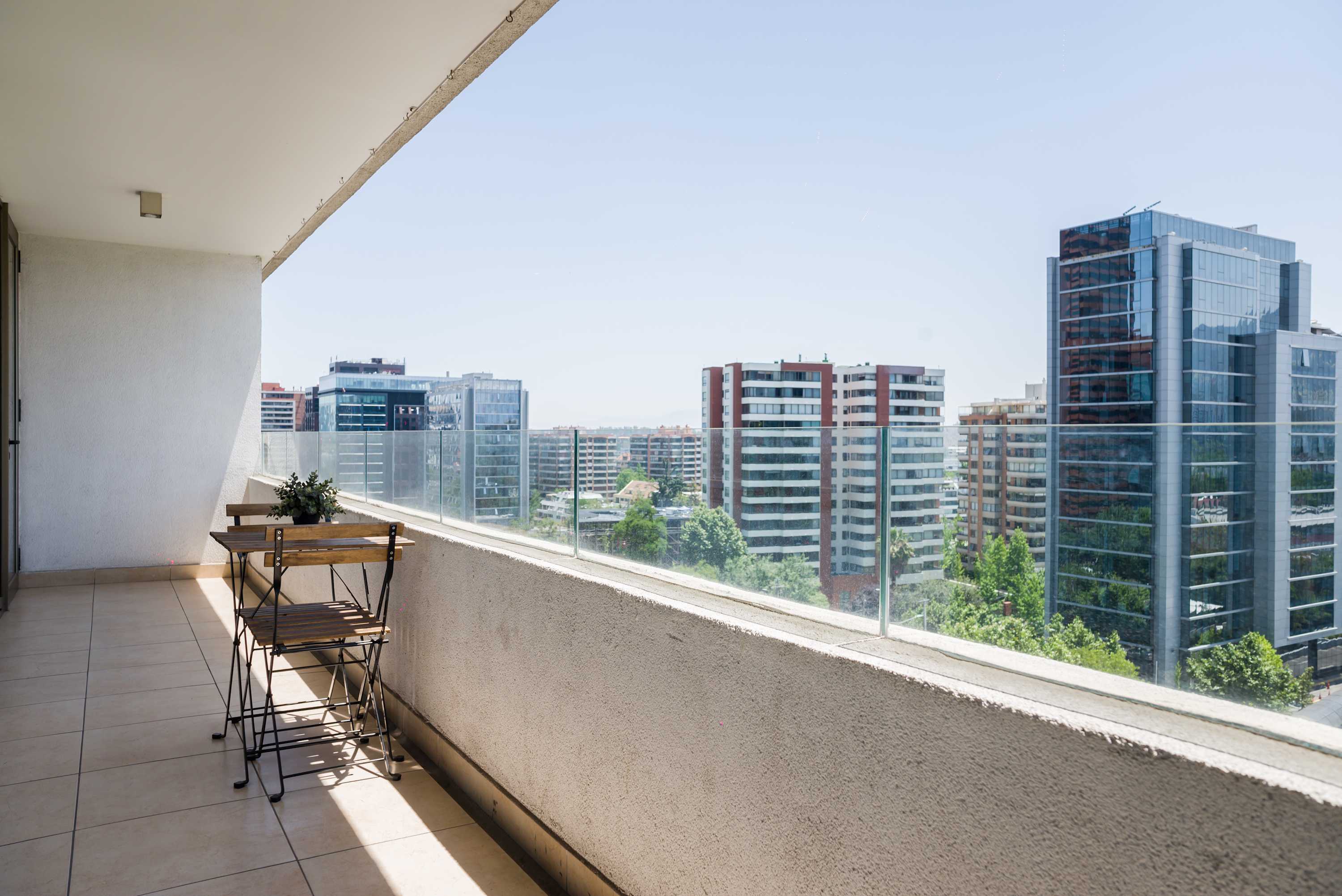 Private balcony with seating for two and expansive views over Santiago’s modern skyline.