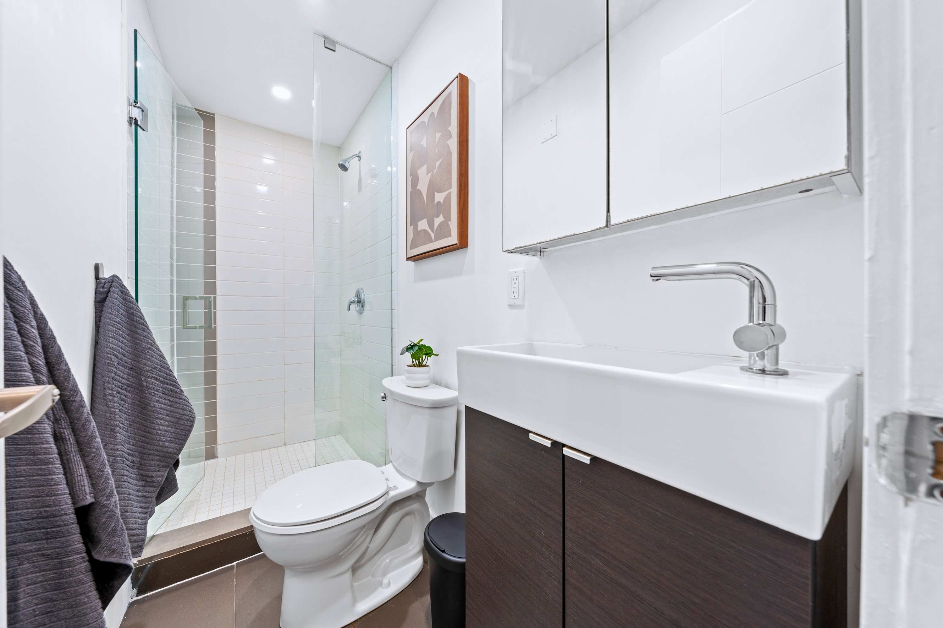 Modern full bathroom with a glass-enclosed shower and vanity storage.