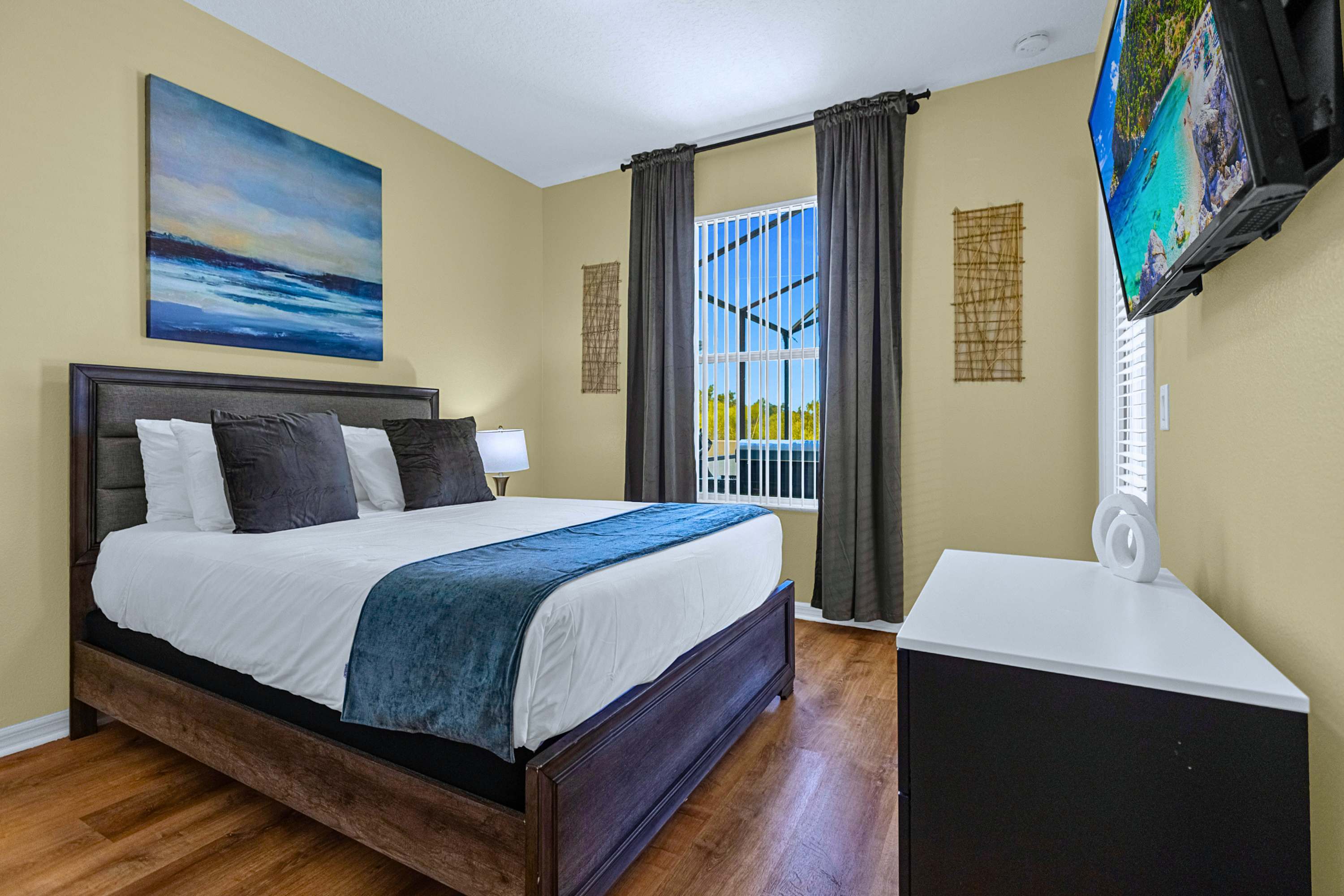Queen bedroom with plush bedding, flat-screen TV, and walk-out access to pool