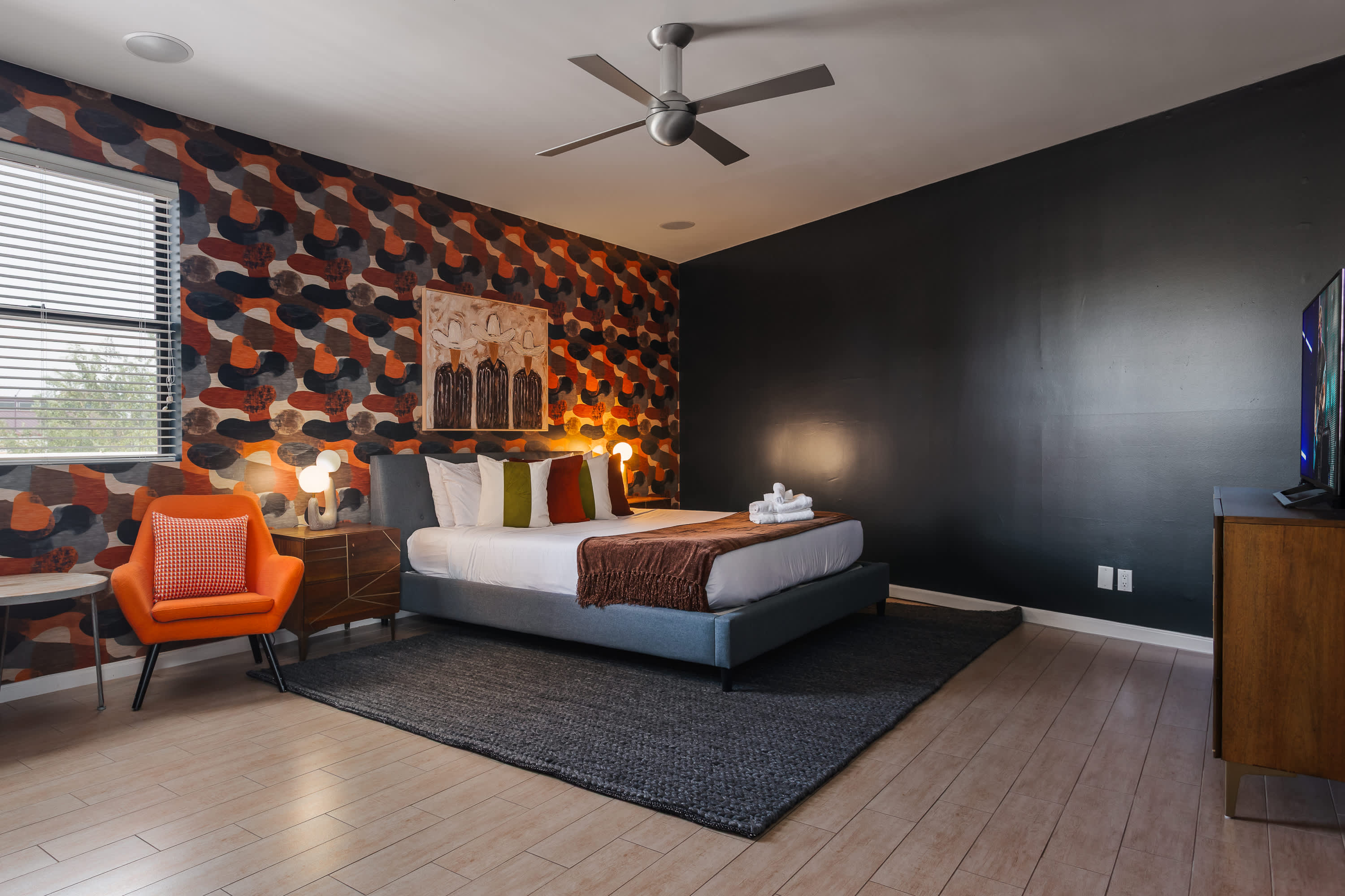 Primary bedroom featuring a King bed, Smart TV, cozy sitting area, private balcony access, and an en-suite bathroom for a relaxing retreat.