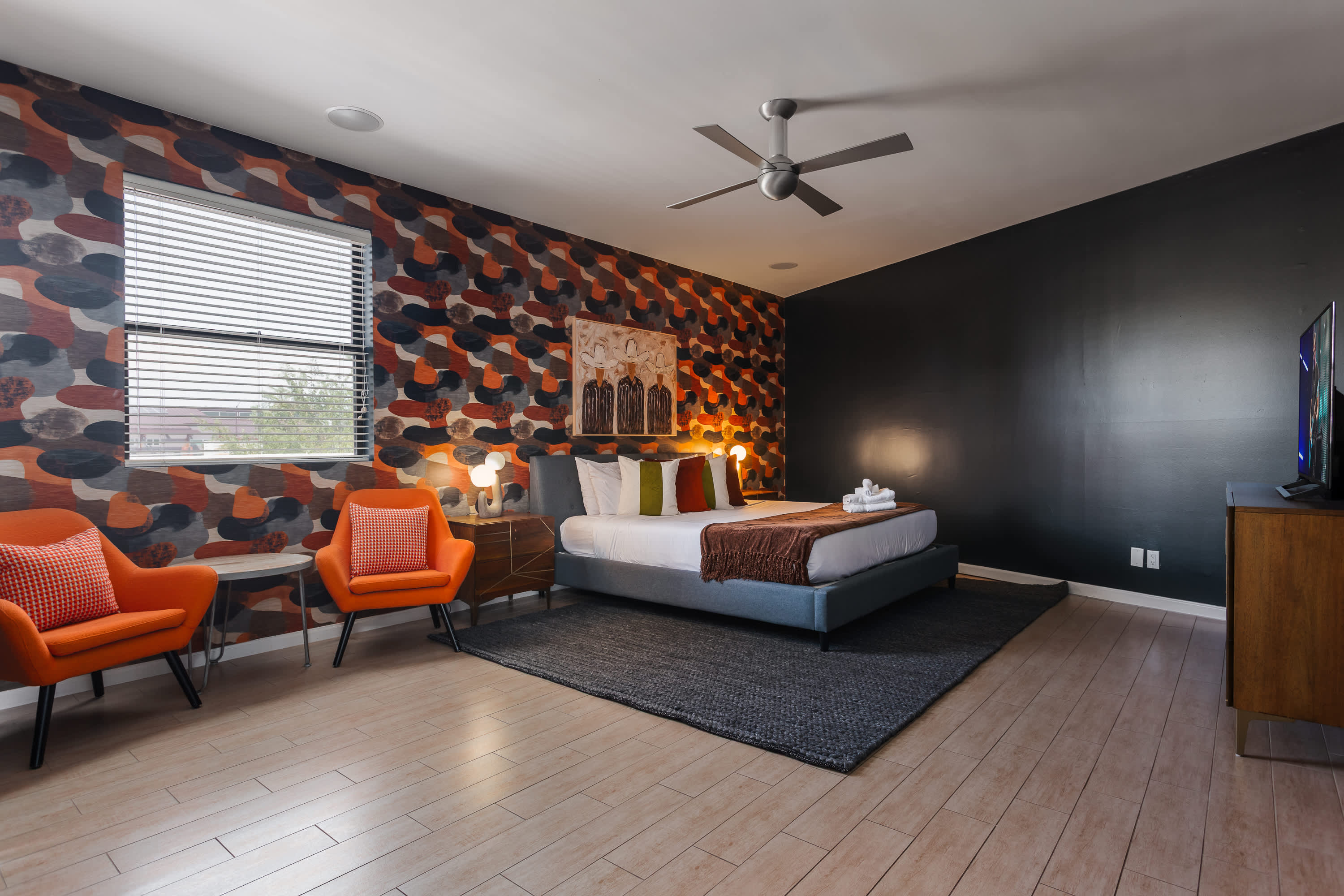 Primary bedroom featuring a King bed, Smart TV, cozy sitting area, private balcony access, and an en-suite bathroom for a relaxing retreat.