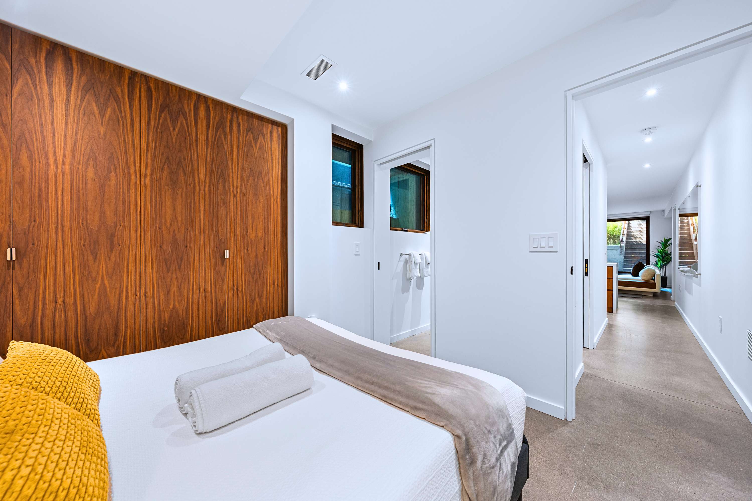 Plush queen bed set against rich walnut paneling with en-suite bath access.