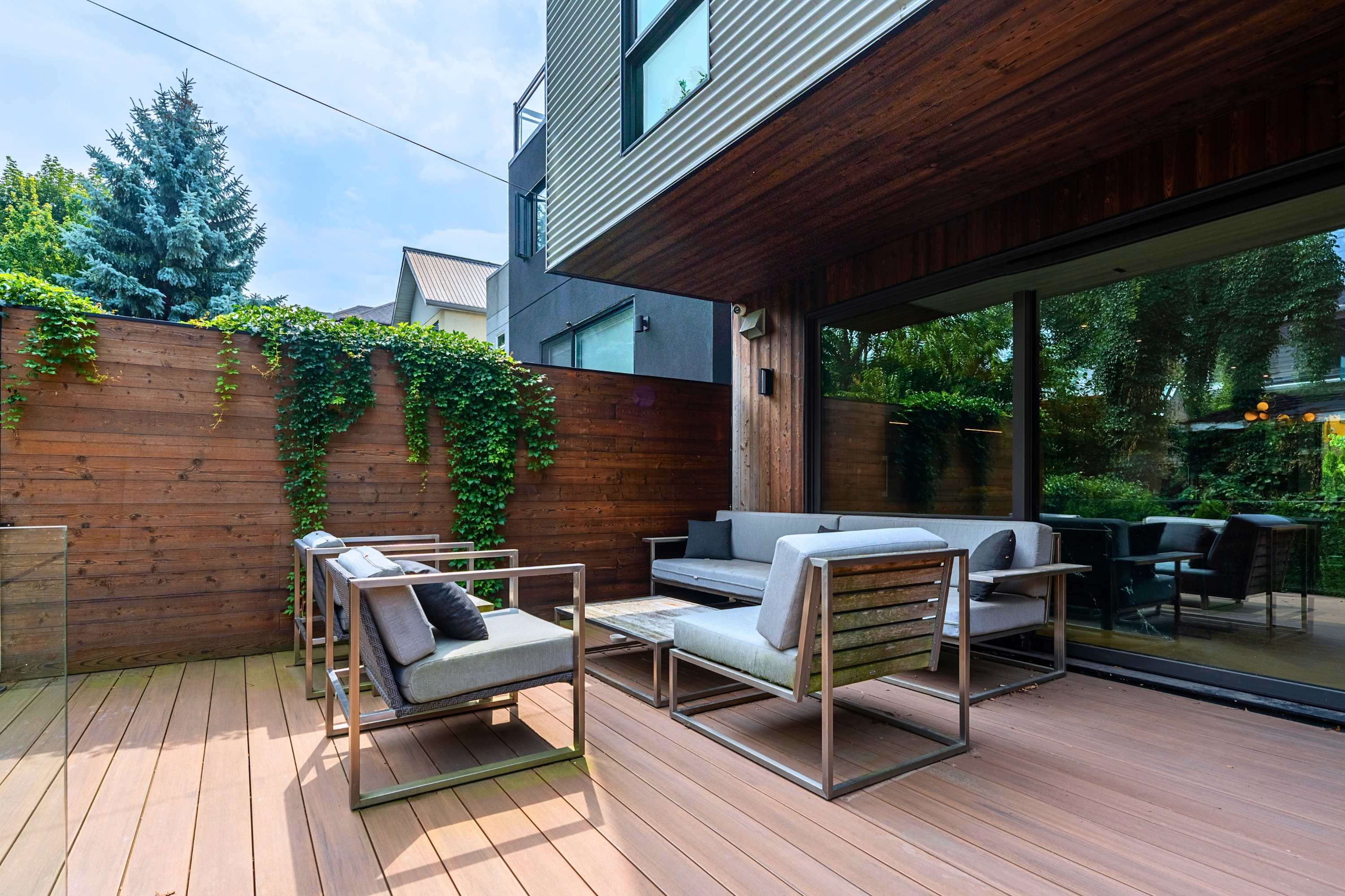 Semi-covered patio lounge with architectural overhang and ivy privacy walls.