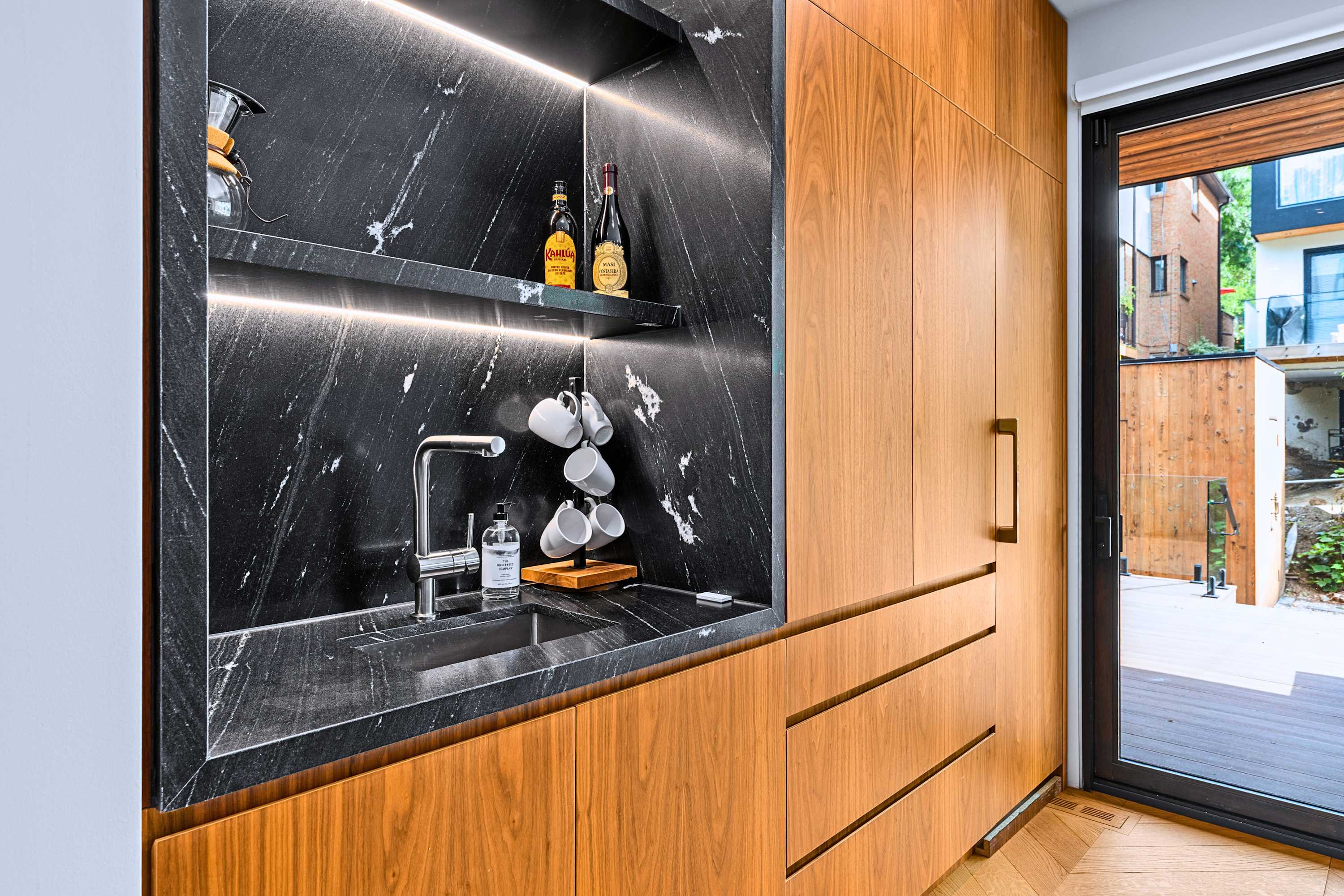 Sleek espresso station with dark marble splashback and warm timber drawers.