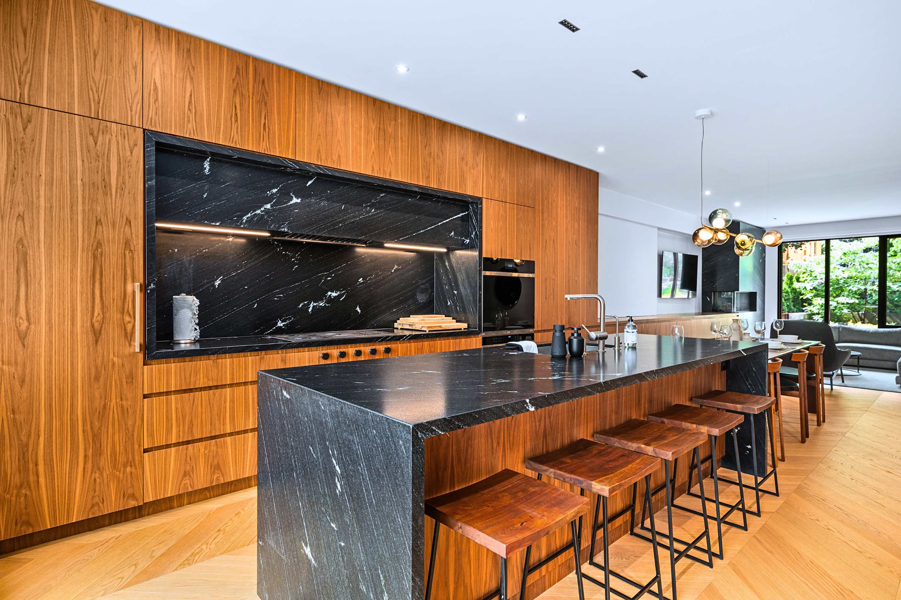 Waterfall stone kitchen island with bar seating and custom dark cabinetry.