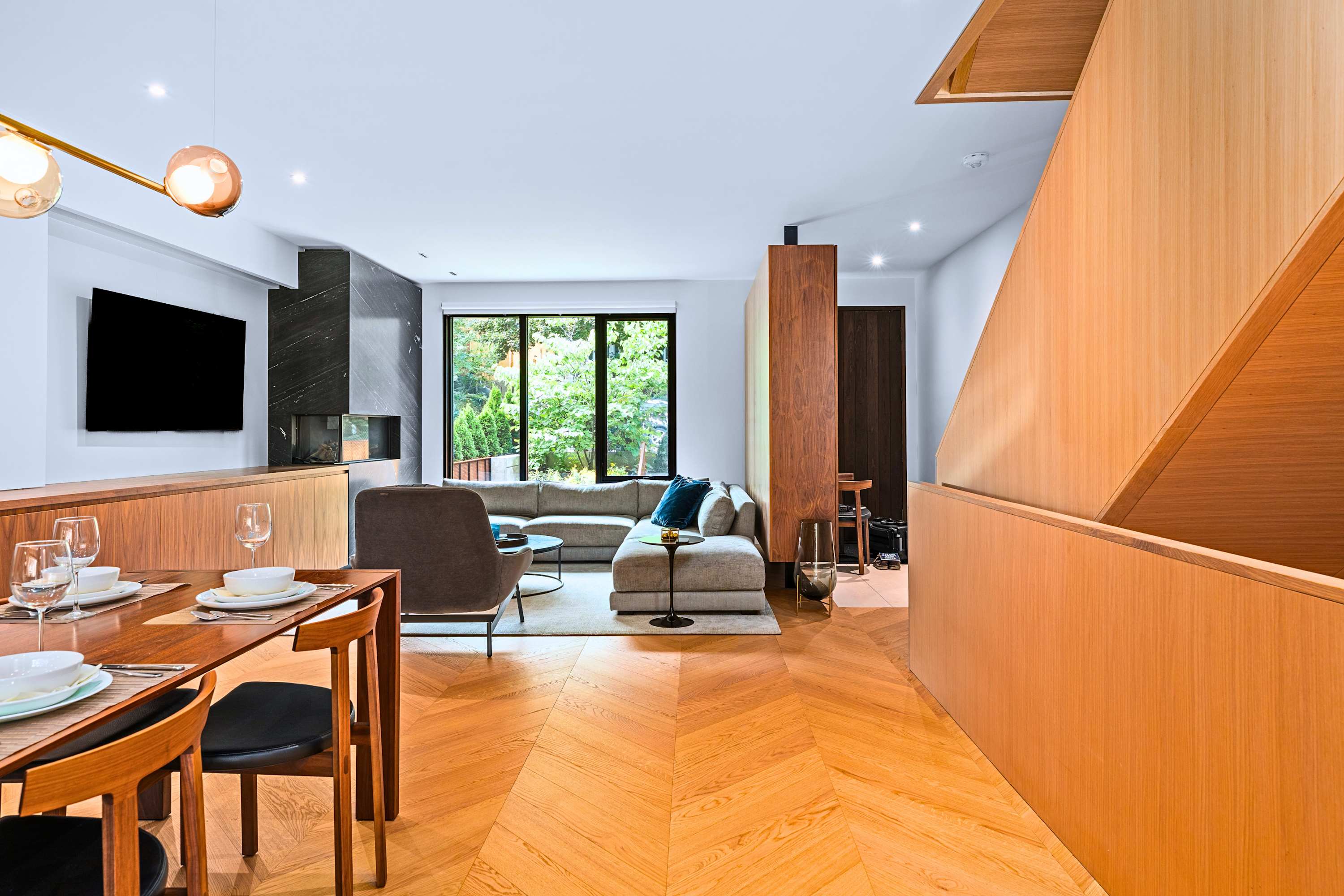 Fluid transition between kitchen, dining, and open stairwell architecture.